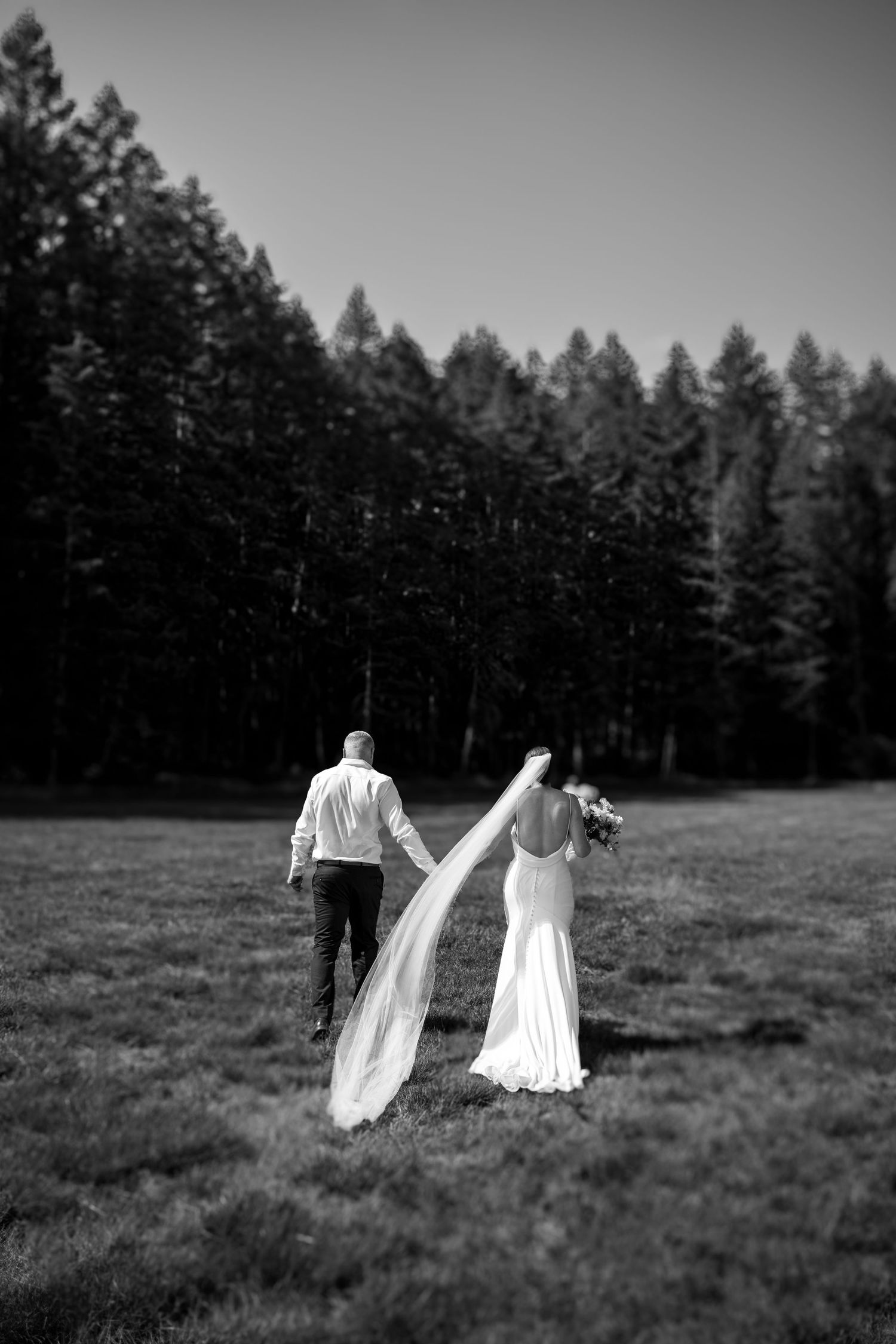 Two figures in white dresses walk across a misty field with dark trees in the background creating an ethereal scene in port Alberni