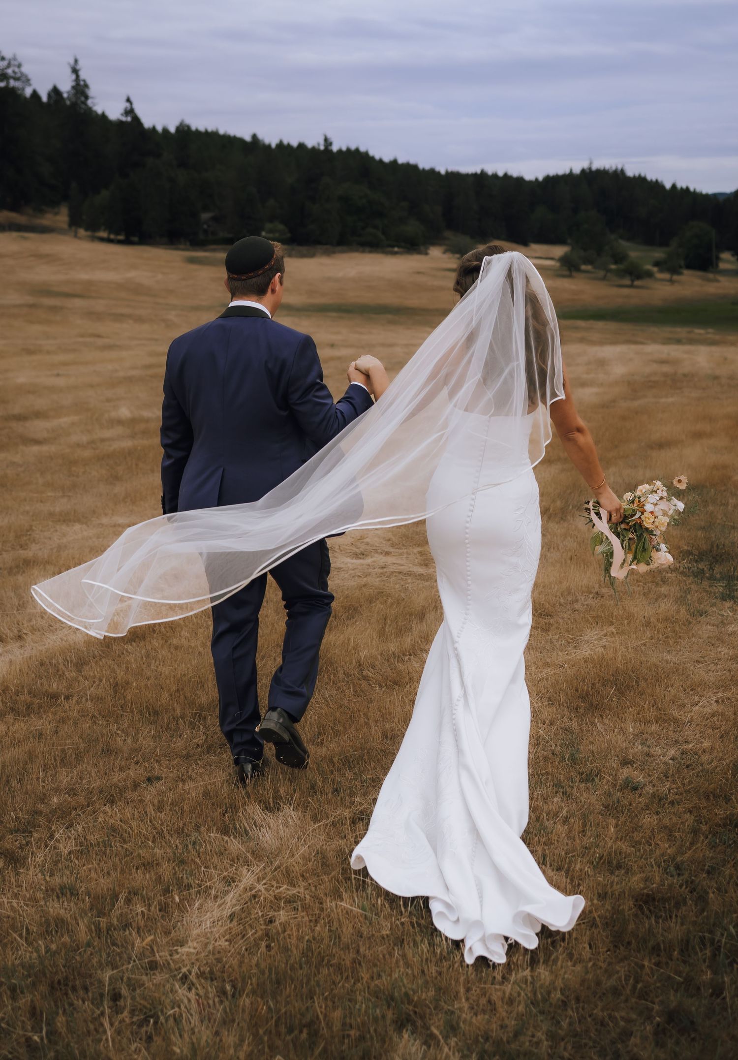 a bride and groom exit their ceremony at stone bridge island farm in a grassy field on salt spring island