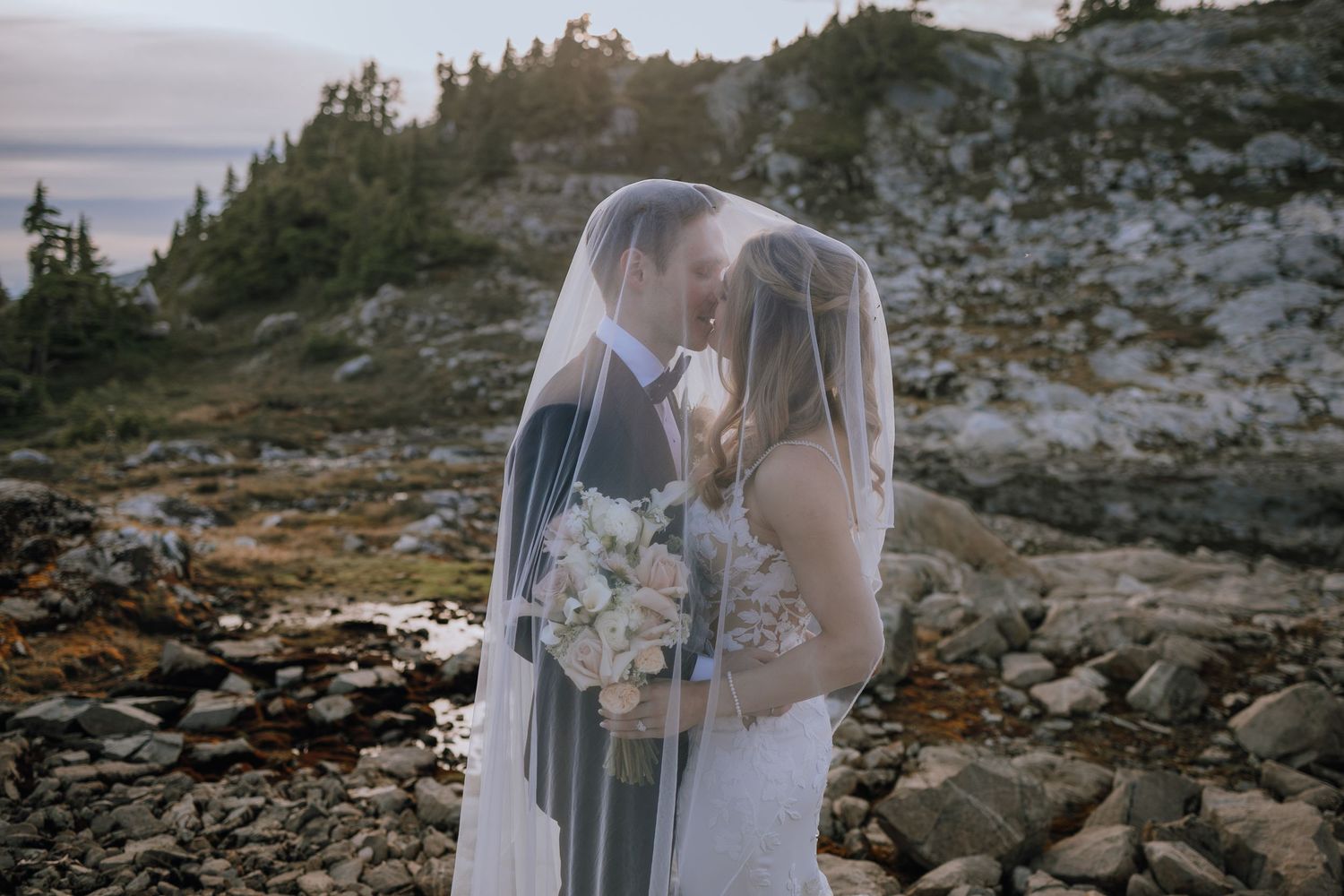 bride and groom under veil on the mountains outside Campbell River on a helicopter tour with 49 north helicopters