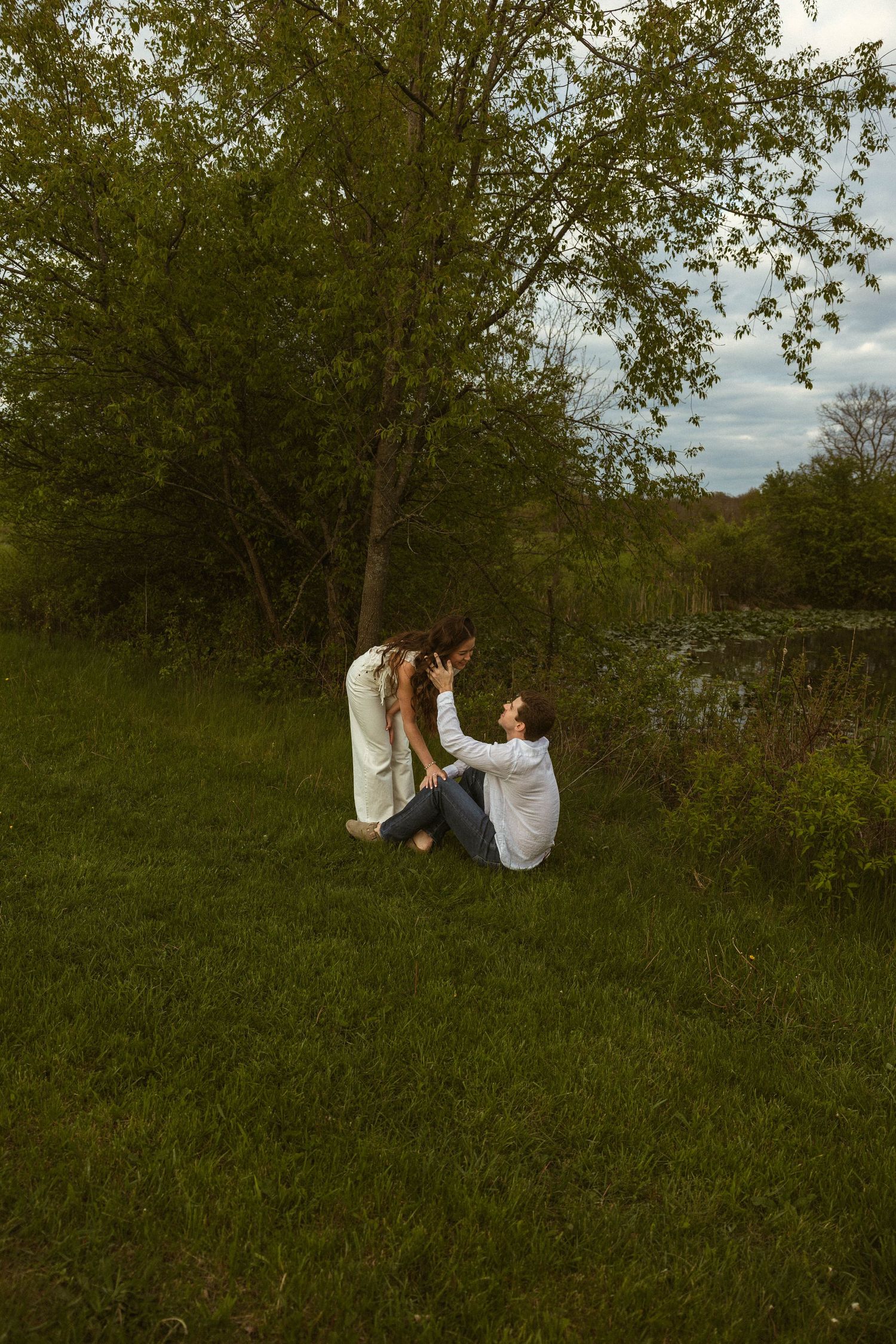Bride sitting in a grassy field during a golden hour engagement session in Ohio.