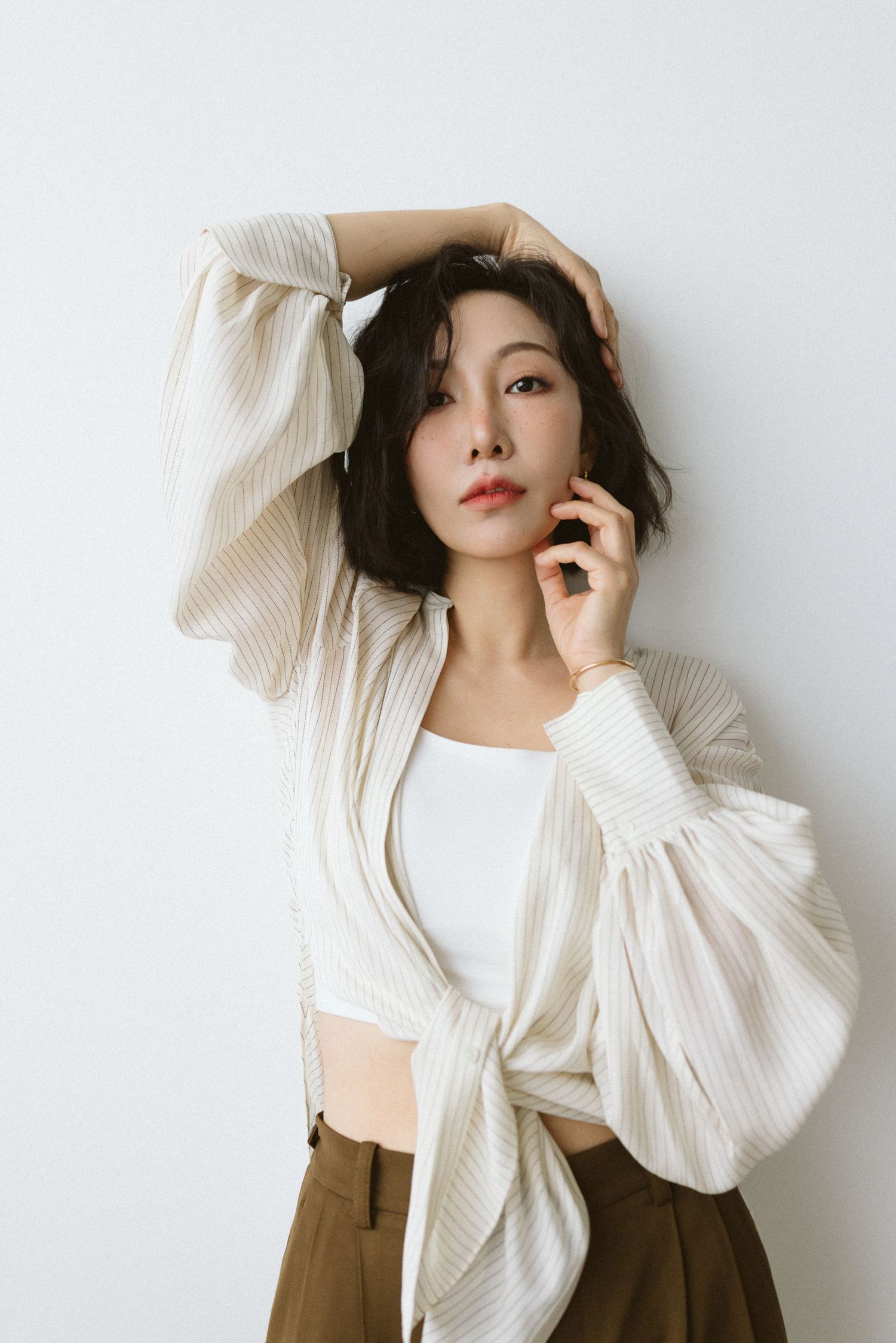 Fashion model wearing white puff sleeve sweater with brown pants in artistic portrait sequence.