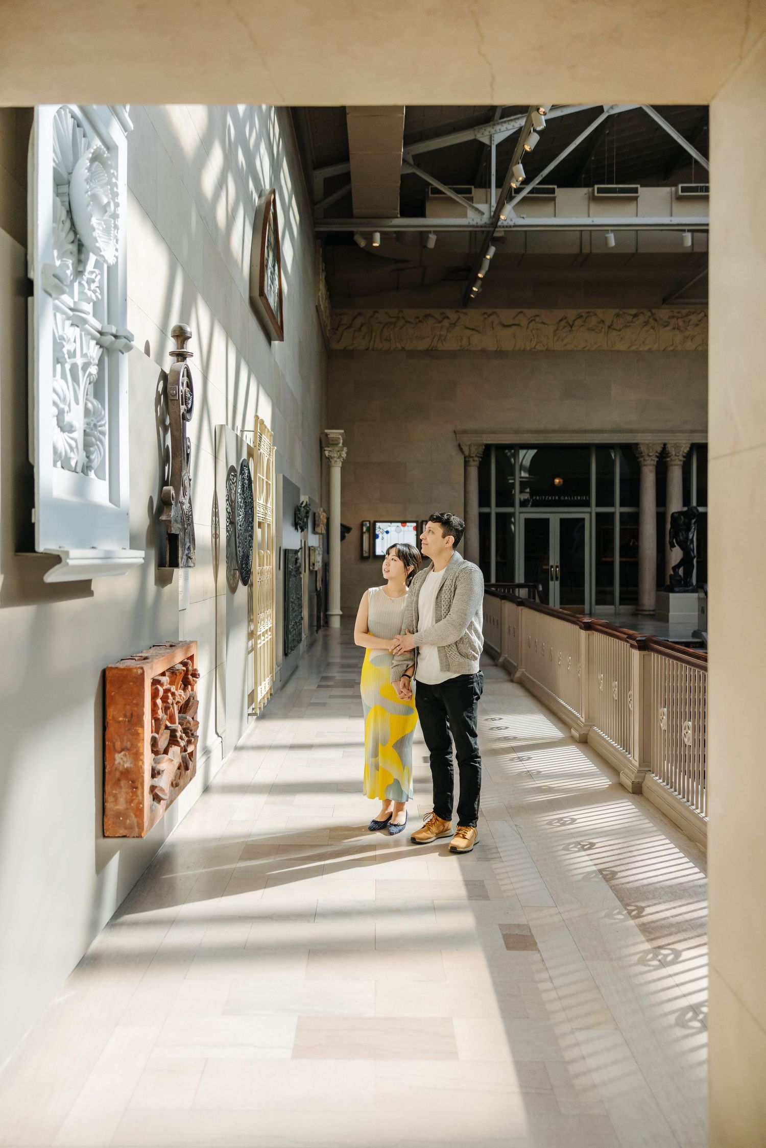 People walking down a bright modern hallway with artwork displayed on white walls.
