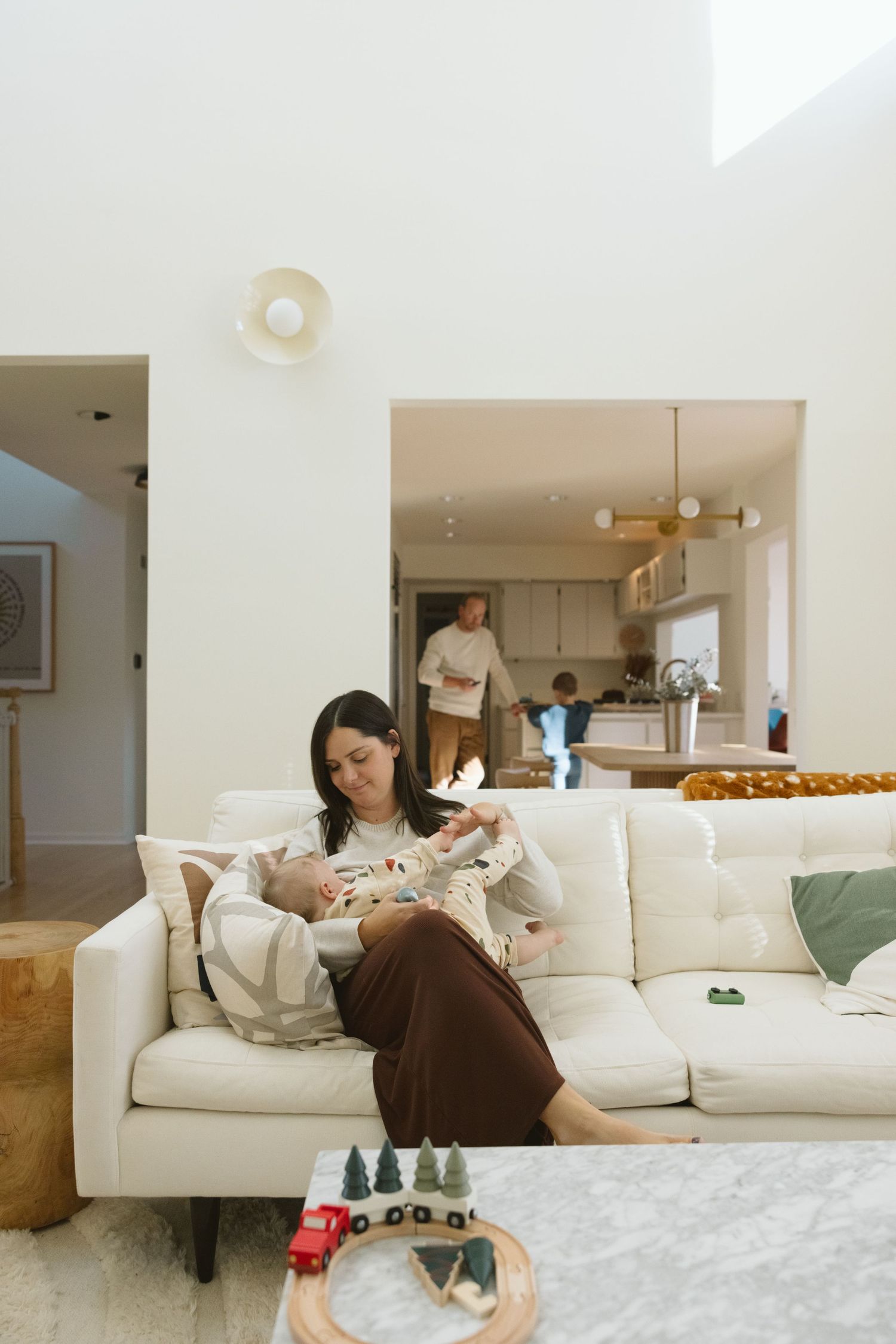 A quiet moment of rest on a white couch with toys scattered on the floor in a modern living room.