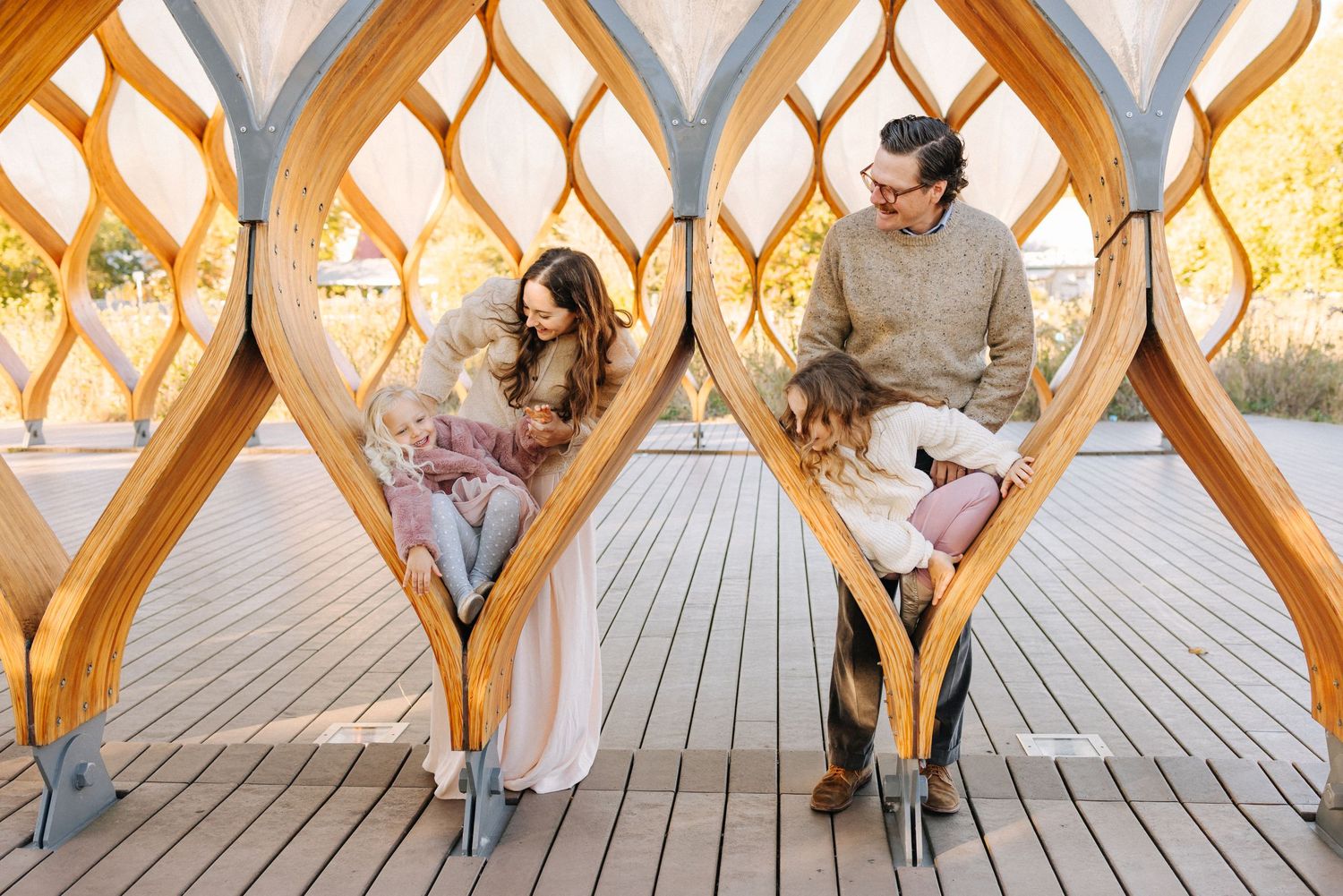 Two people sit close together on a wooden porch with a diamond-patterned railing during sunset.