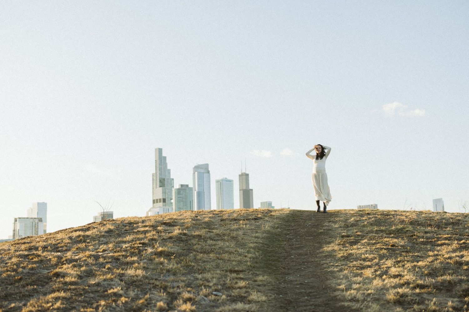 Figure silhouetted on hill with downtown Los Angeles skyline in distance.