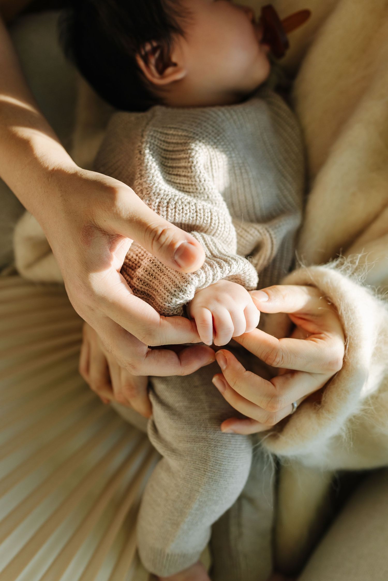 Close up of hands gently holding a soft knitted textile in natural light.