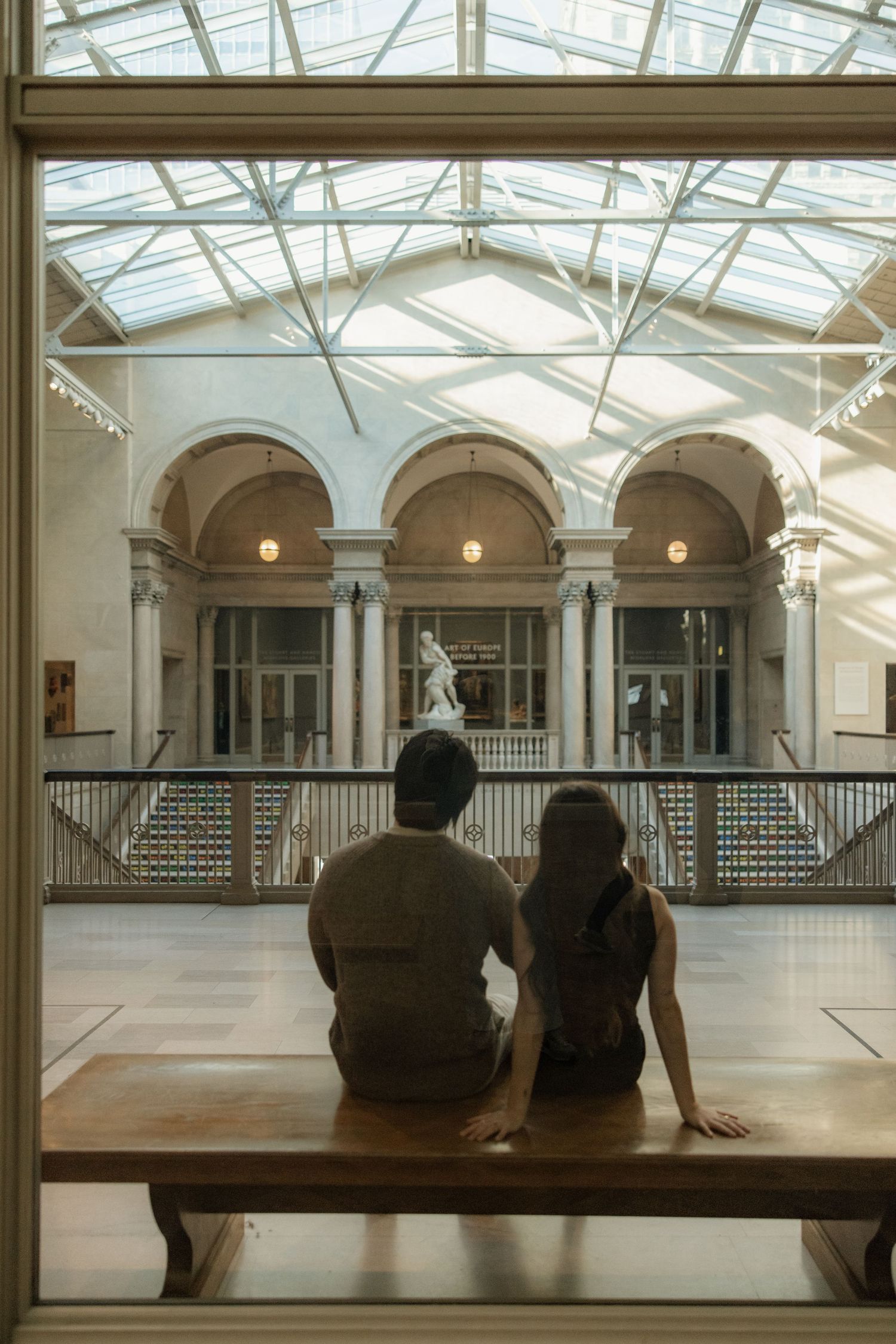 People admiring the architecture of a grand indoor space with skylight and arched gallery.