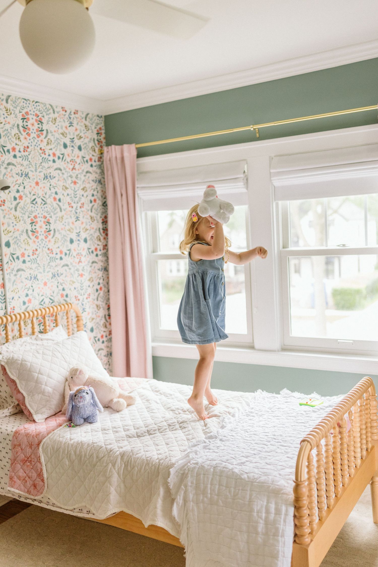A series of three photos showing a child jumping on a white quilted bed with wooden frame and floral wallpaper background.