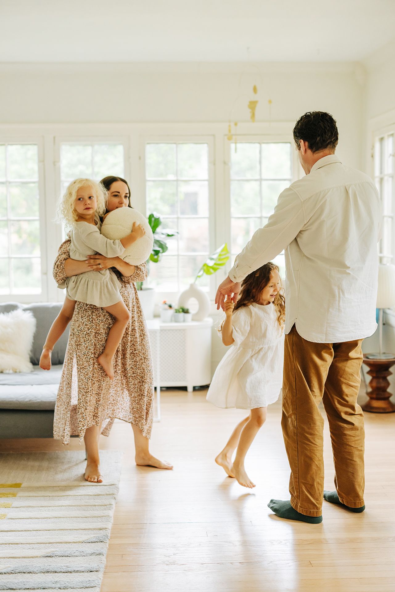 A family dancing together in their bright, sunlit living room on a lazy afternoon.