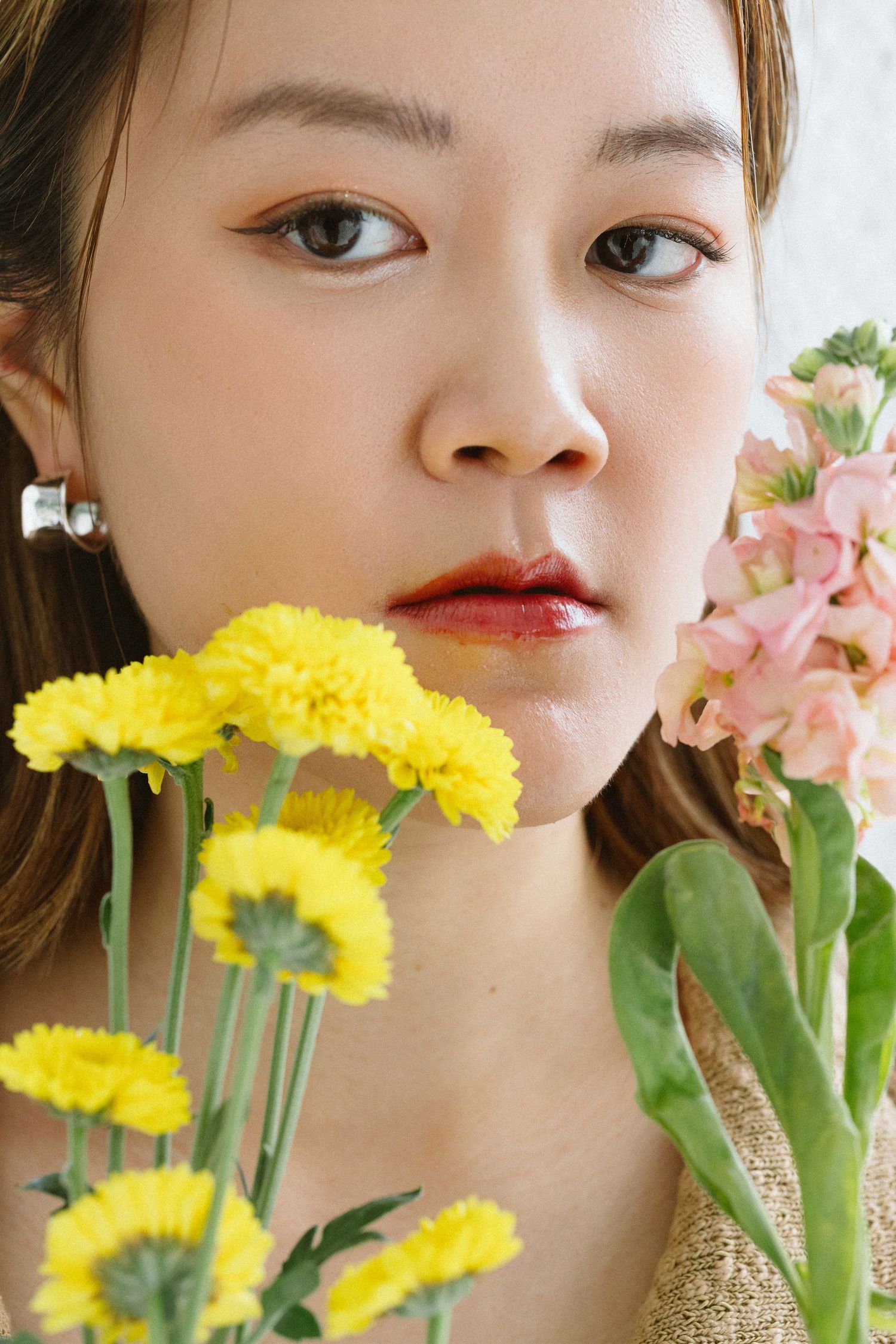 Close-up beauty portraits with yellow and pink flowers in soft lighting.