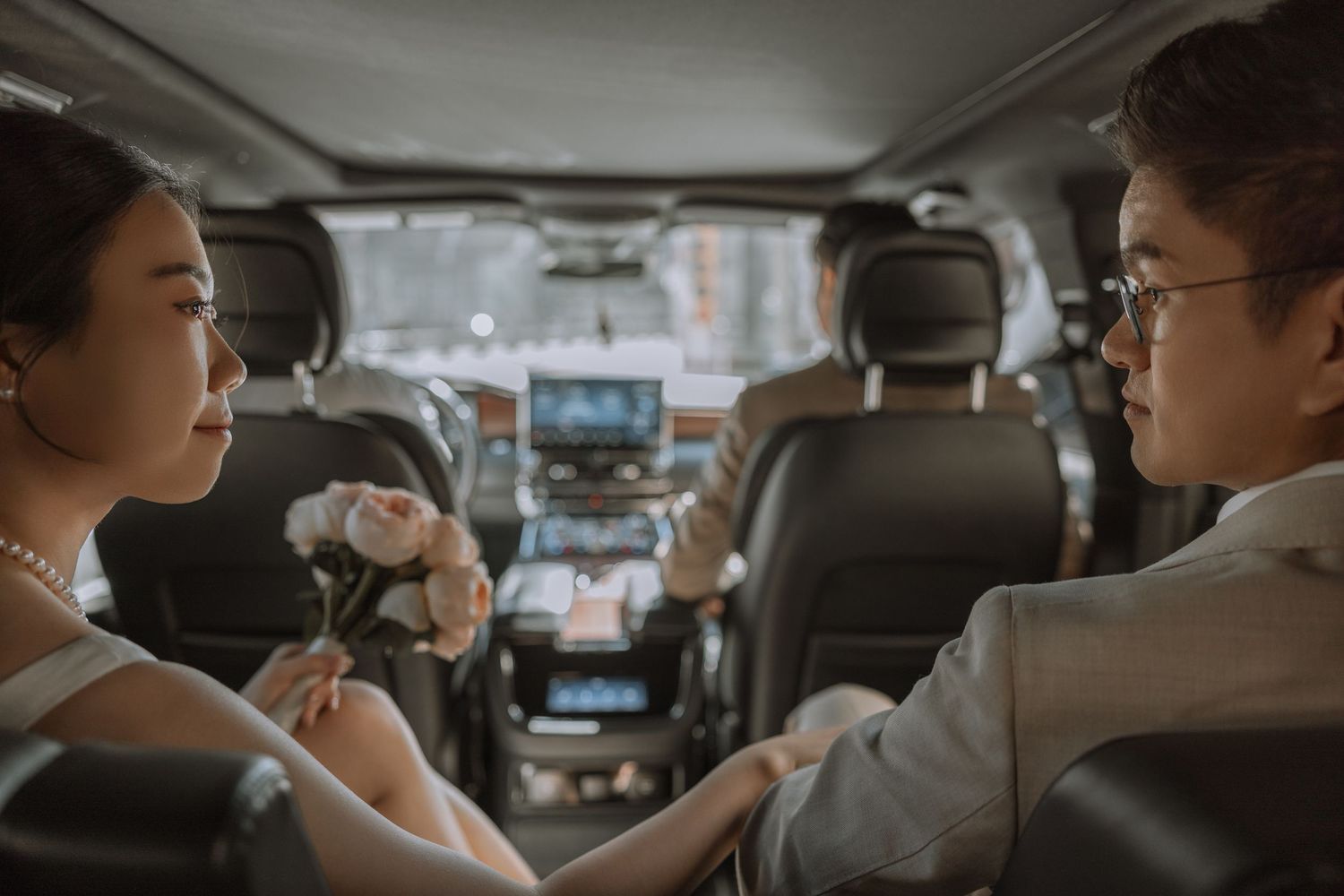 Interior of car showing passengers in wedding attire during intimate moment.