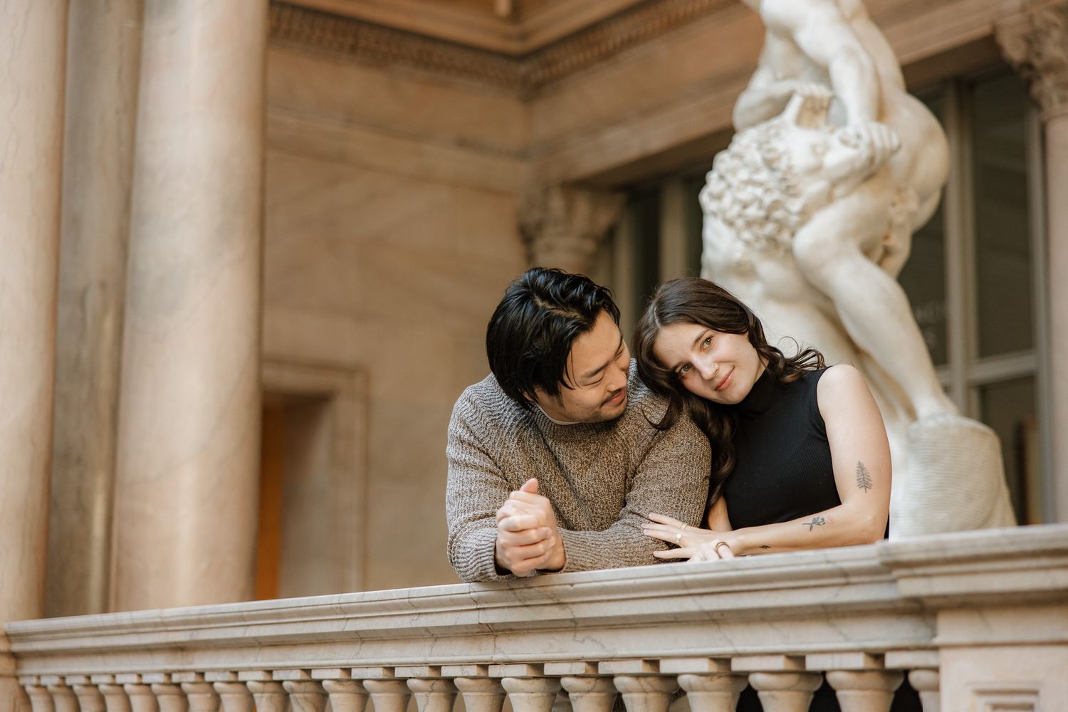 A couple studying together at a museum or gallery with a classical marble statue in the background.