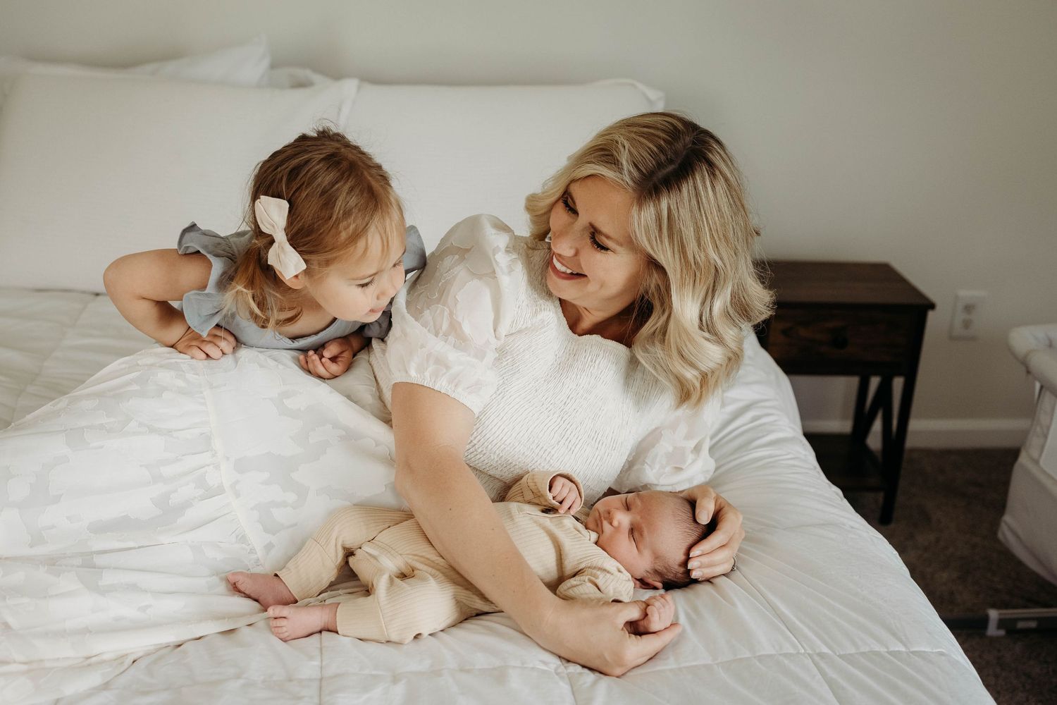 Family sharing intimate moments together on white bedding in natural light.