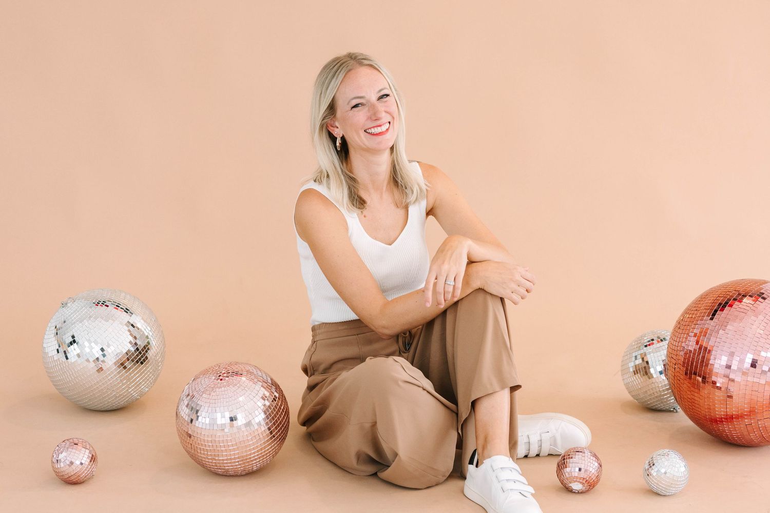 Professional lifestyle photography with decorative silver and rose gold disco balls against a peach background.
