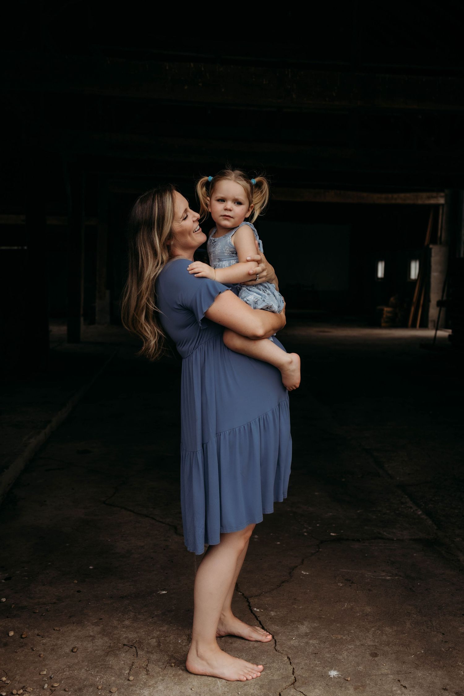 Mother and child share tender embraces in a series of intimate indoor portraits wearing blue dresses.