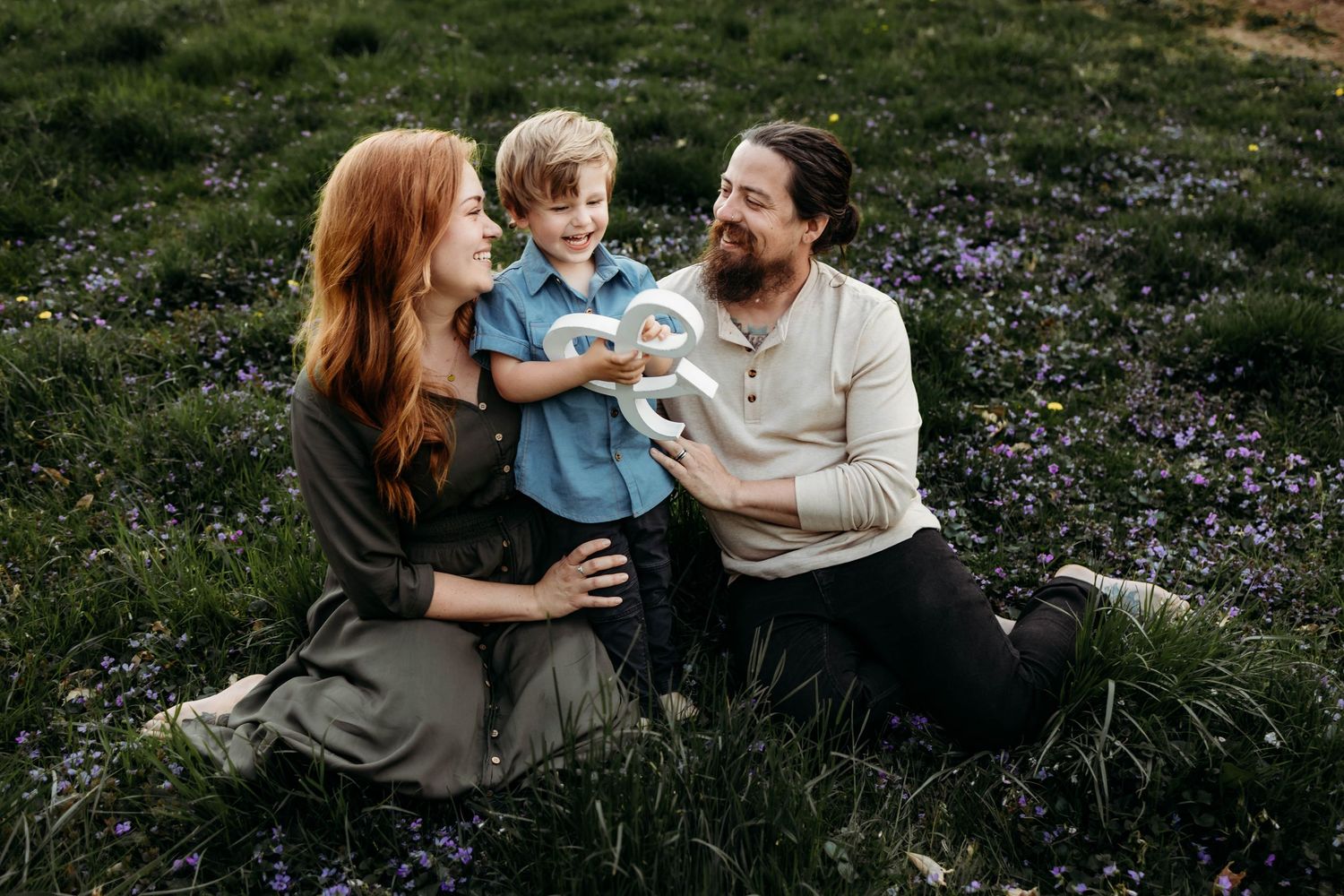 Family enjoying tender moments together while sitting in a flower-filled meadow.