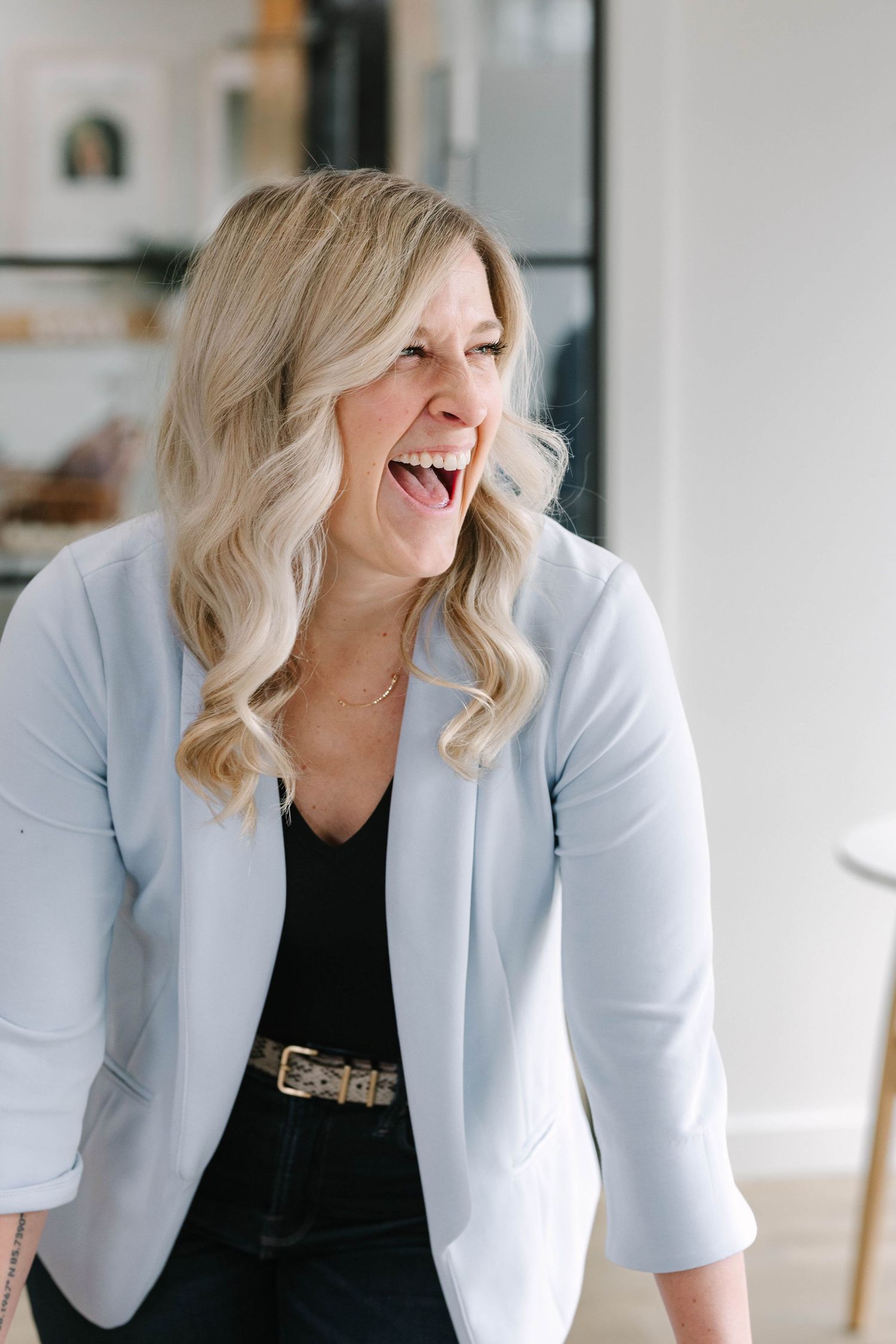 Professional headshots in light blue blazer showing genuine expressions and laughter.