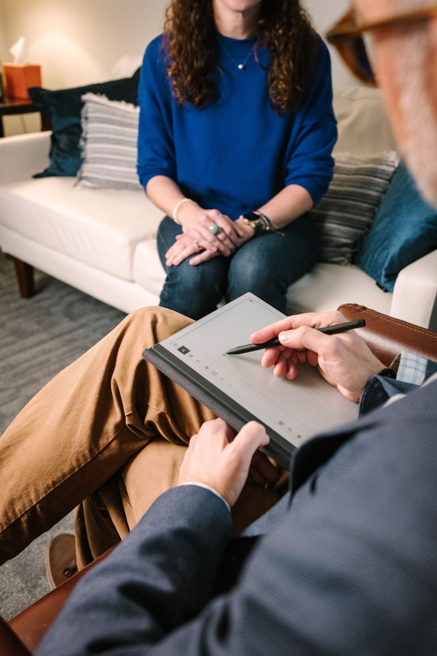 Counseling session showing someone taking notes while sitting on a couch.