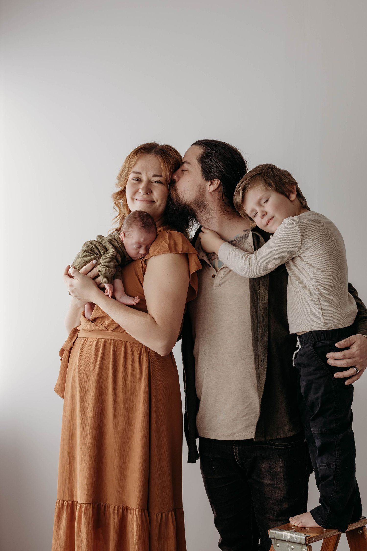 Family sharing intimate hugs and embraces against white studio background.