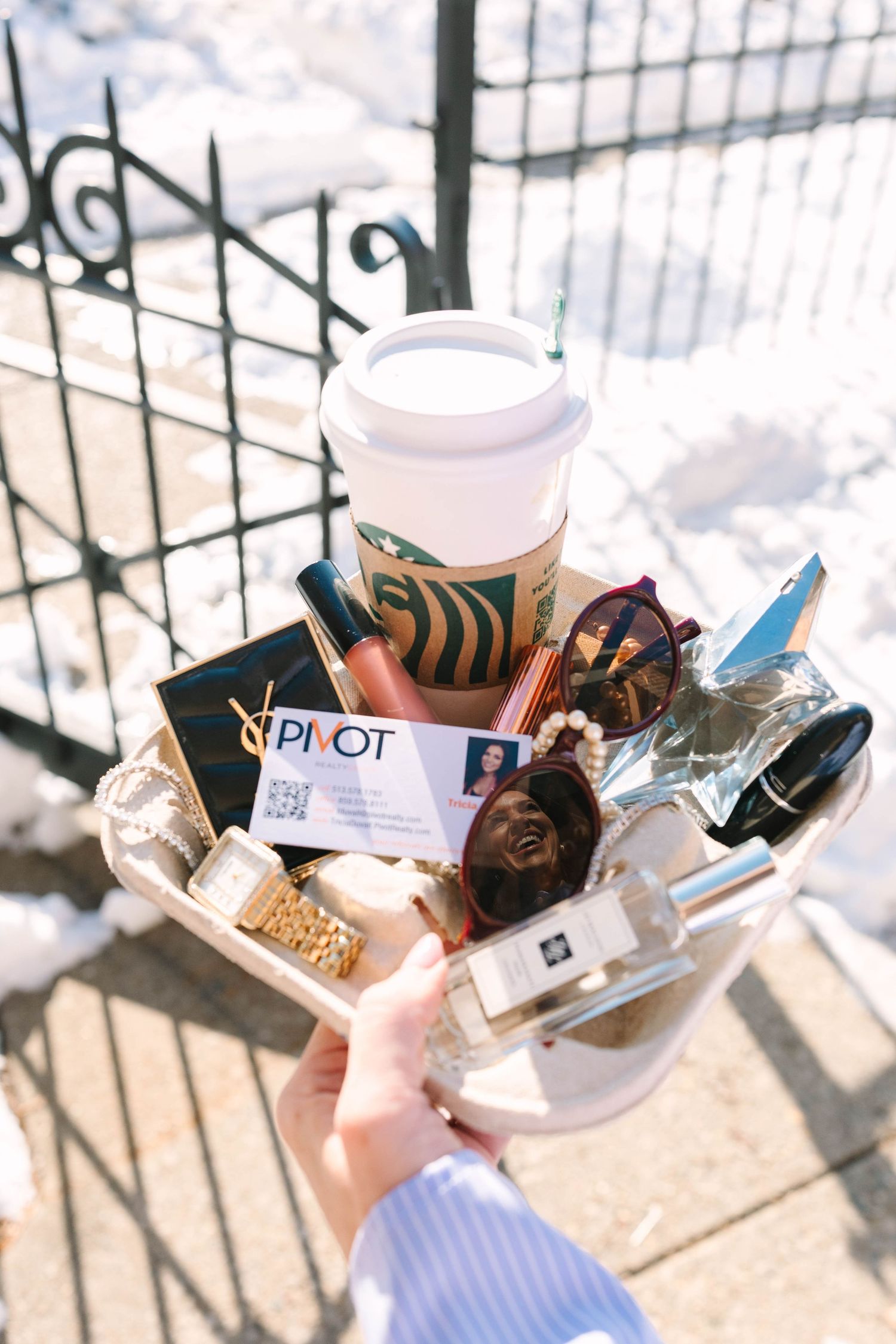 Multiple disposable coffee cups and trash items scattered on a concrete surface near metal railings in sunlight.