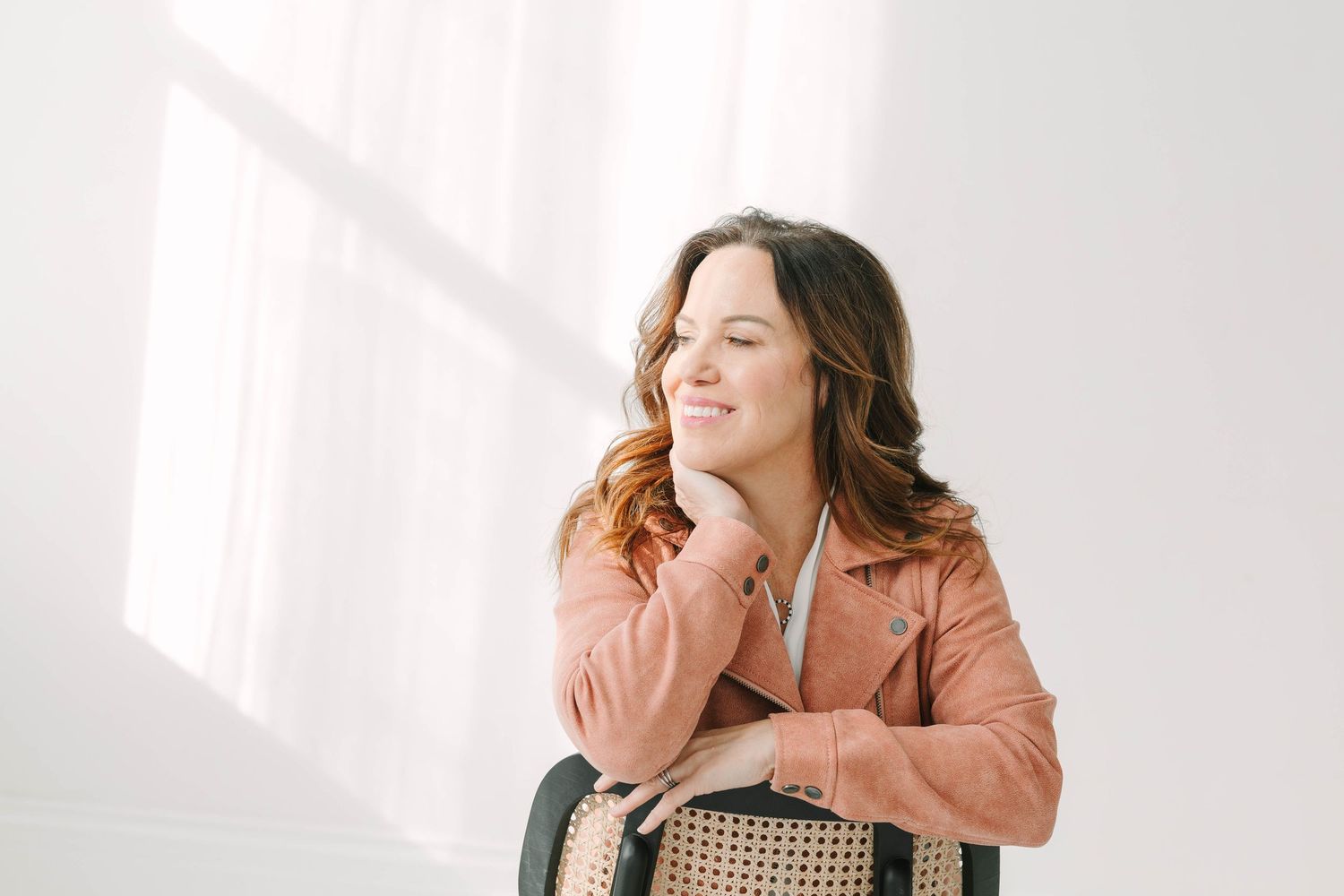 A person in a peach-colored blazer poses against a white wall in a series of candid expressions.