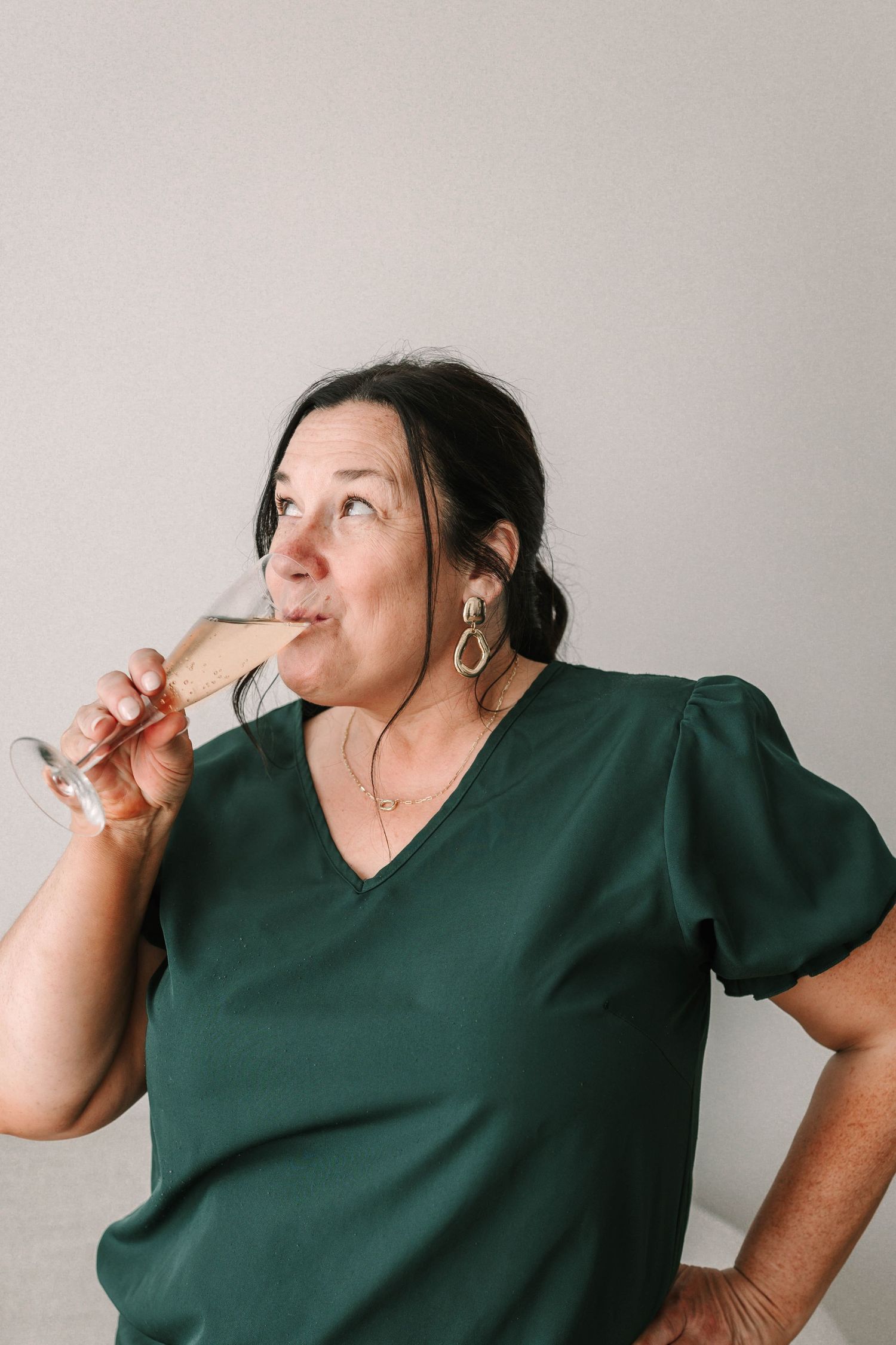A series of photos showing someone in a dark green top taking sips from a glass against a light gray background.