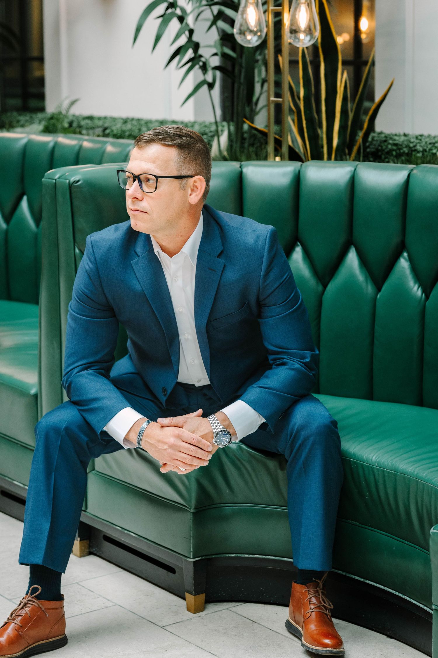 Business portrait series featuring navy suit against emerald green tufted couch.