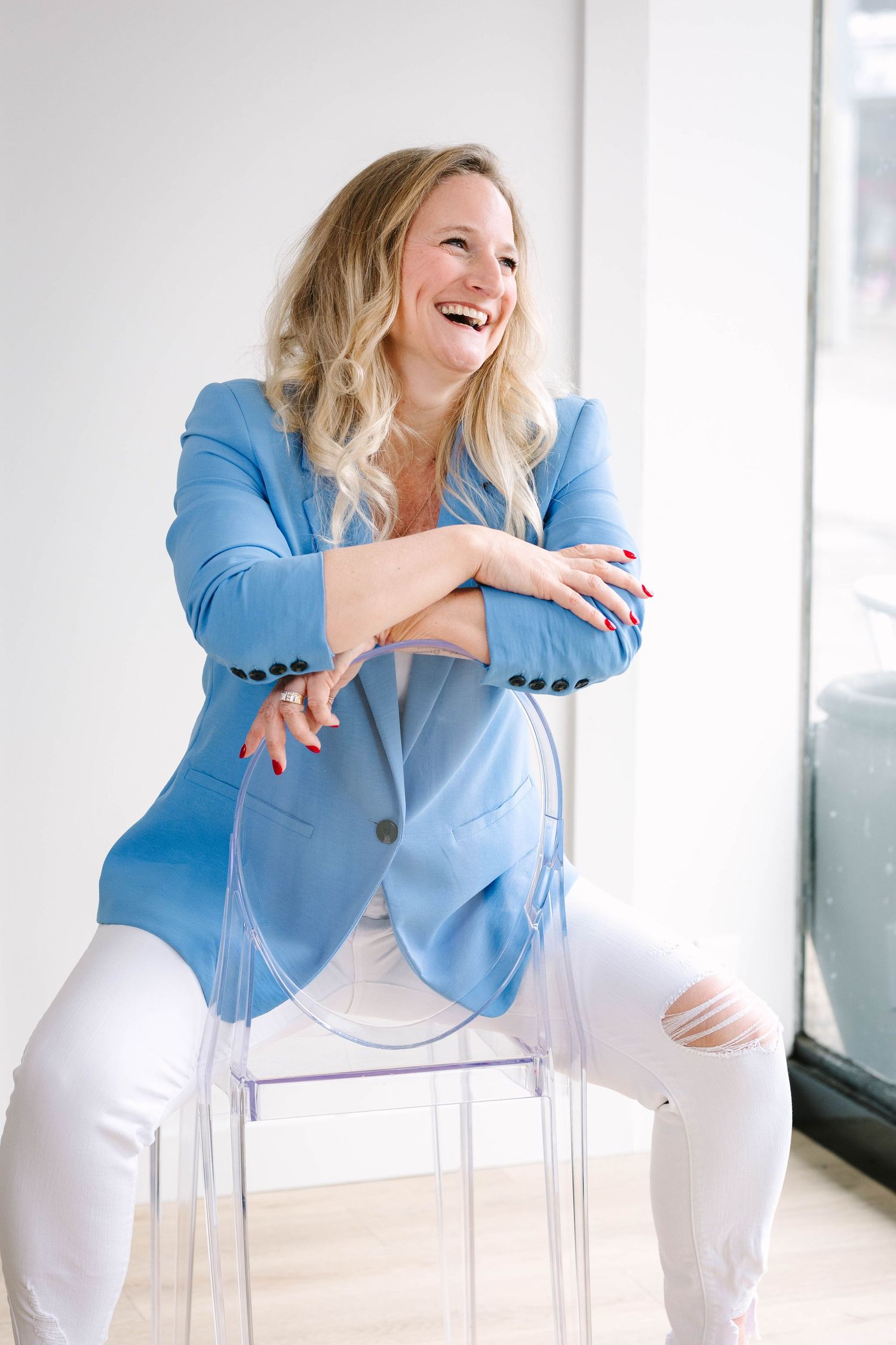 Professional photoshoot featuring bright blue blazer and white pants in minimalist setting.
