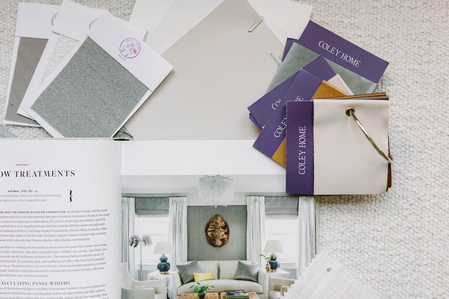 Interior design materials including fabric swatches and magazine layouts on white surface.