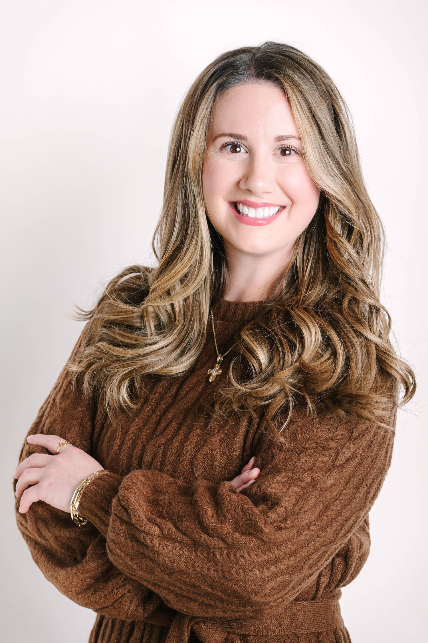 Studio portrait of a woman in brown sweater against white background.