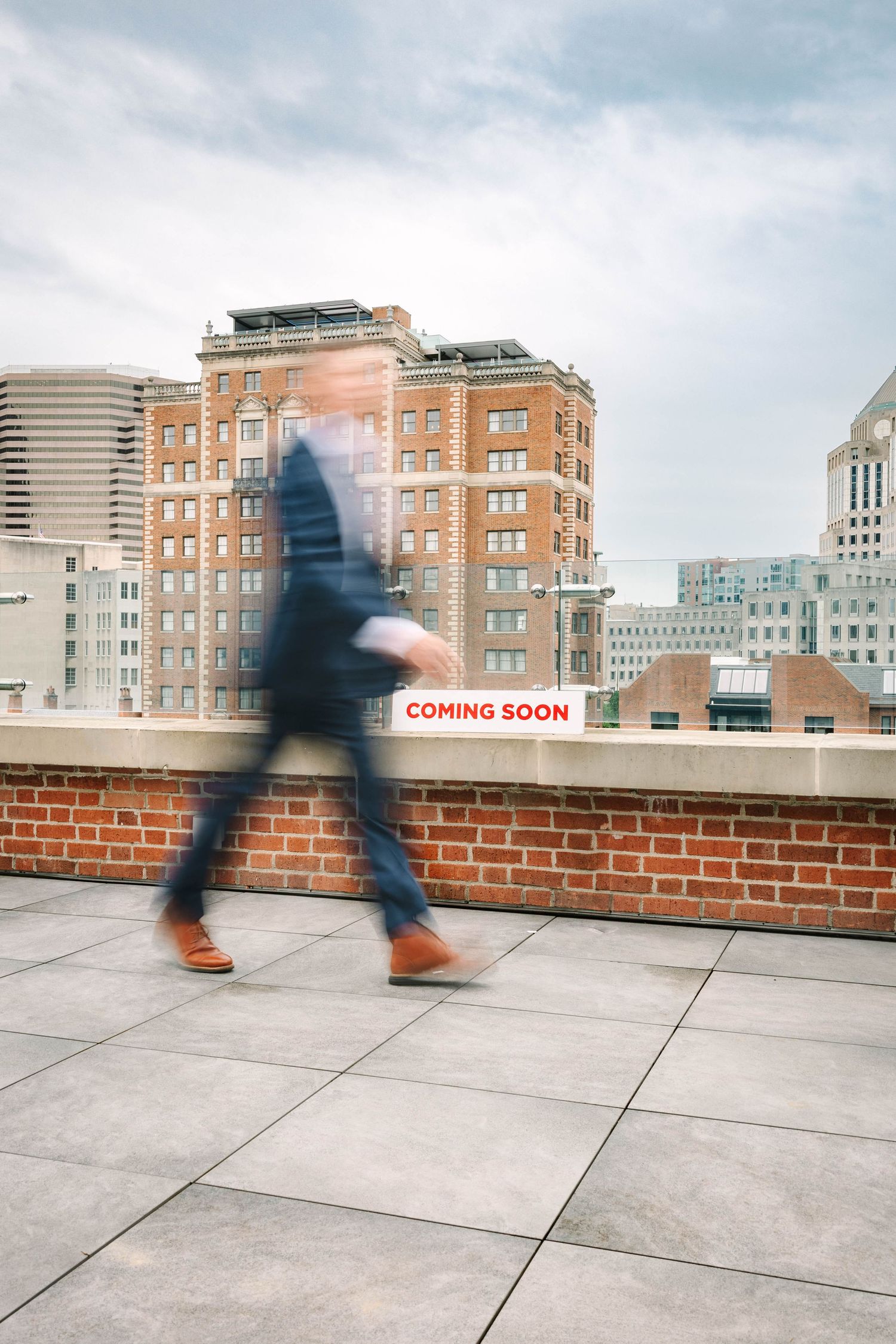 Urban rooftop sequence showing walking legs against city skyline with brick wall.