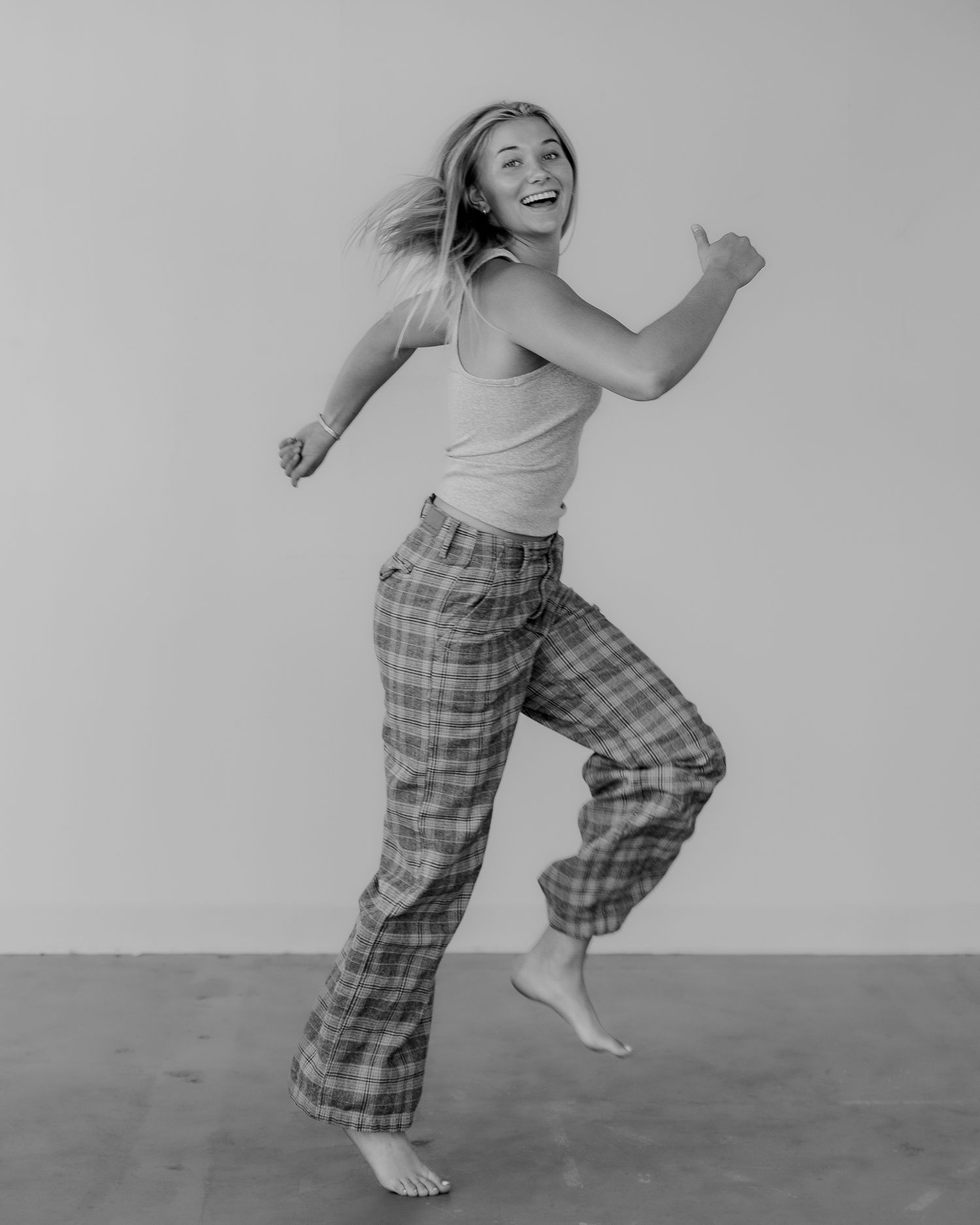 Dynamic black and white photos capture playful movement in plaid pants against minimal backdrop.