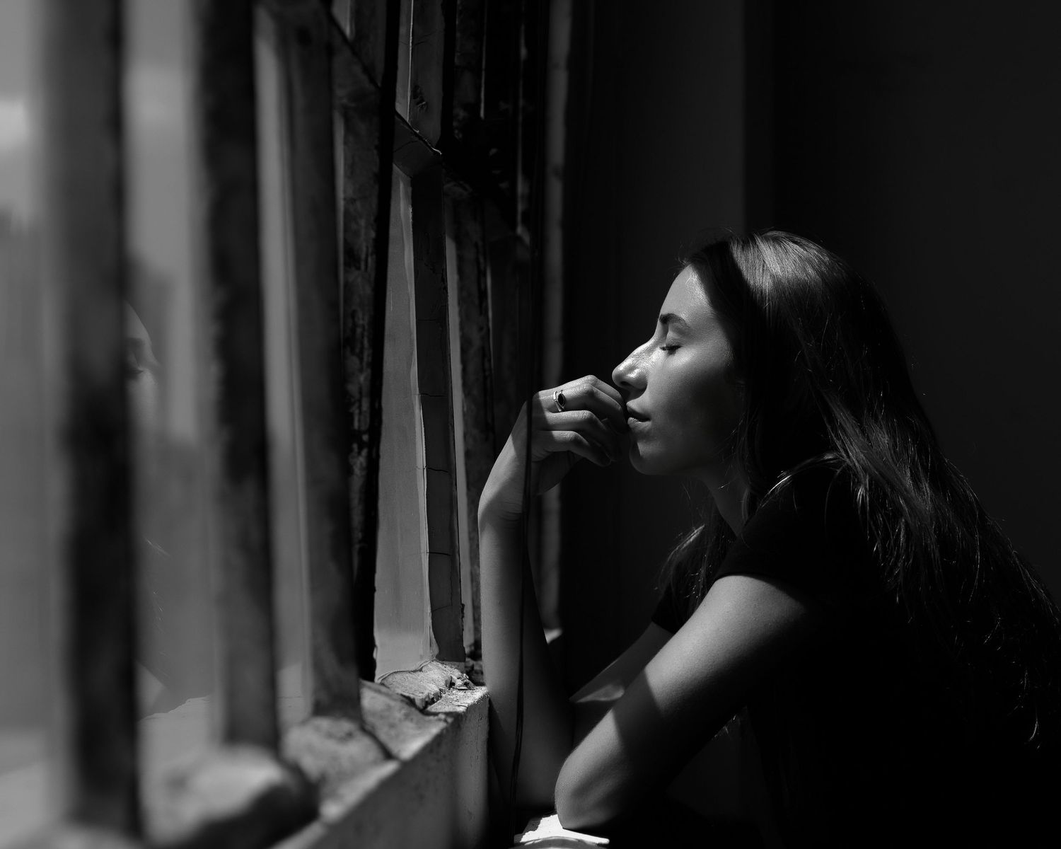 Moody black and white portraits showing contemplative poses near window.