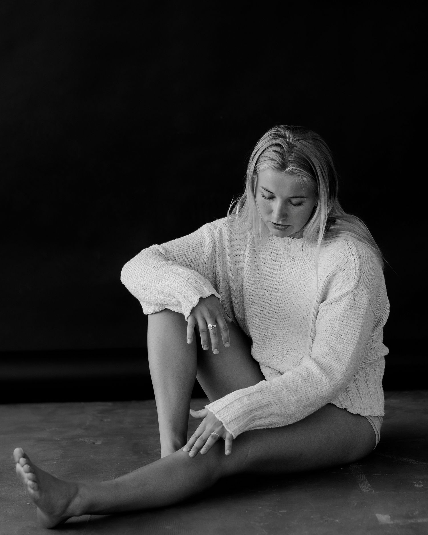 Dramatic black and white photos of figure in white clothing lying on dark floor.