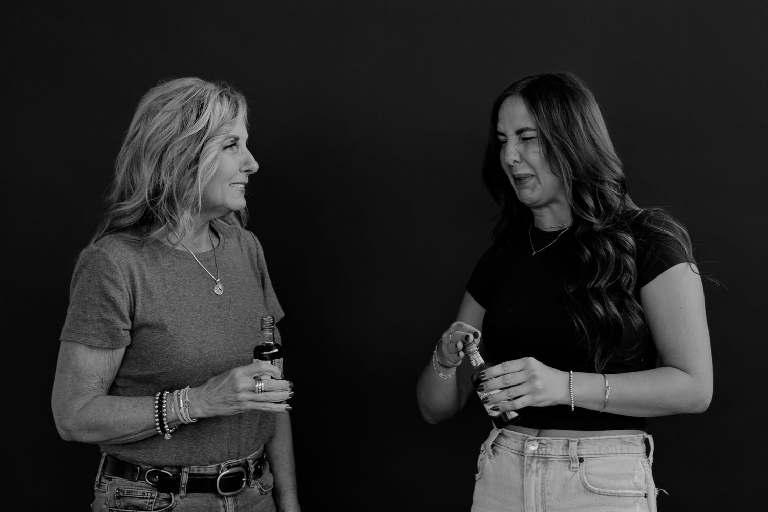Two women standing close and smiling during a black and white studio photography session.