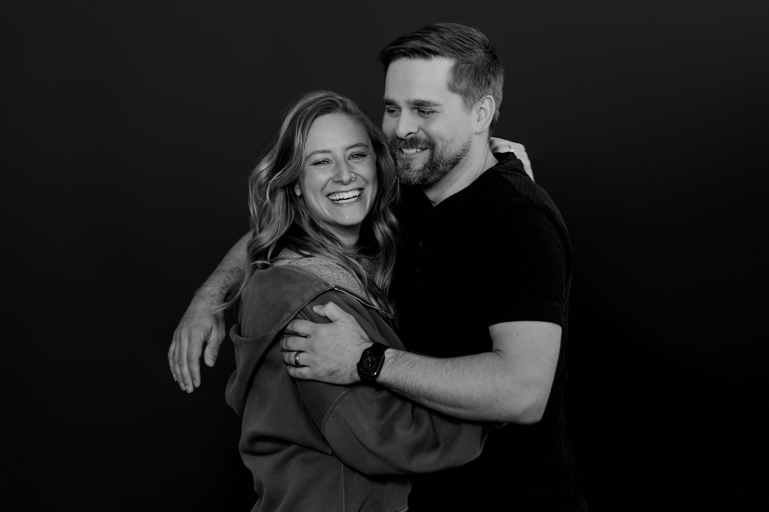 Couple sharing authentic moment of happiness in monochrome studio setting.