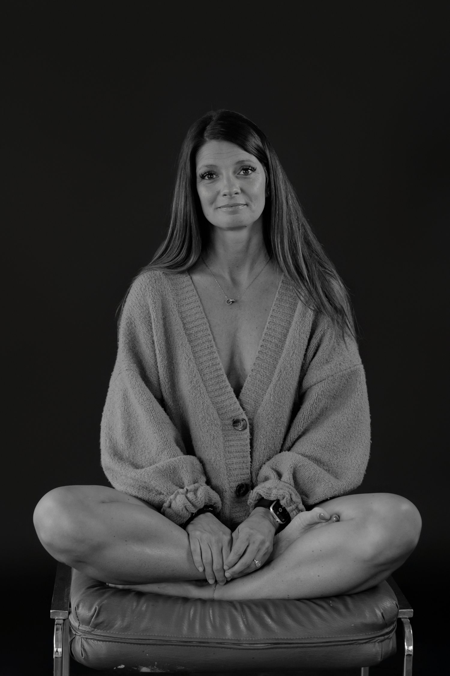 Black and white portrait series of someone wearing a cozy cardigan sweater against dark background.