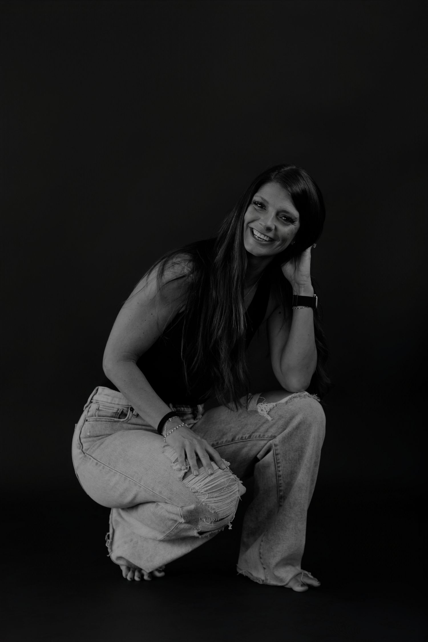 Low-key black and white photography showing crouched poses in light clothing.