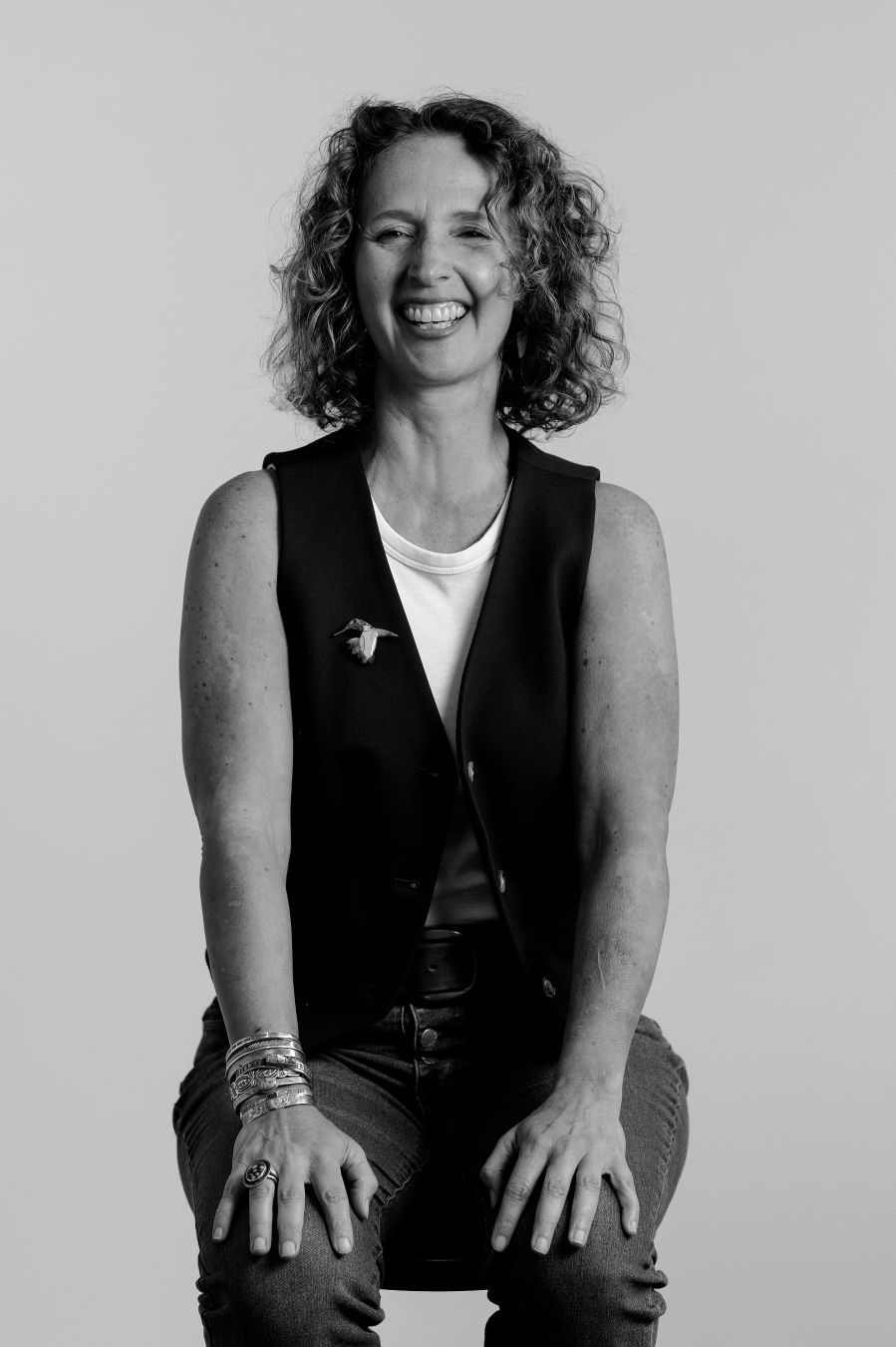 Person in black vest poses expressively on light background in monochrome portrait series.