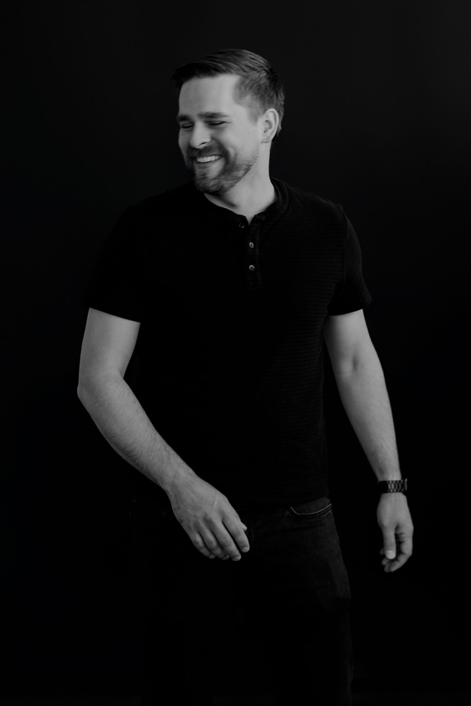 Person in black polo shirt shown laughing in dramatic black and white portraits.