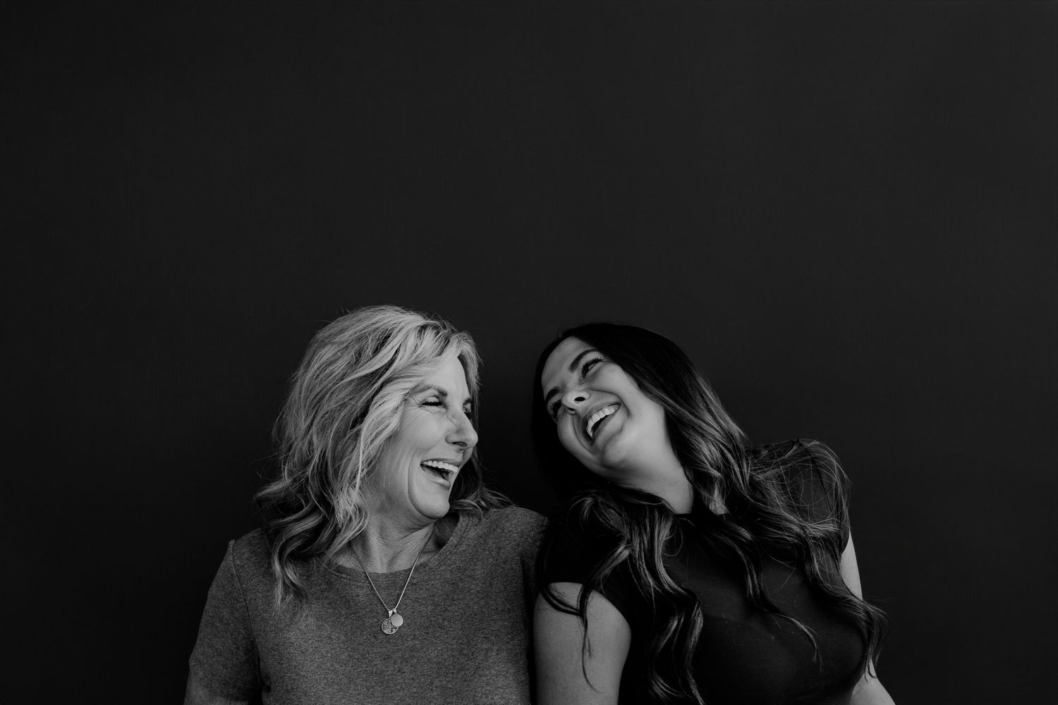 Two women sharing genuine laughter during a casual studio photography session.