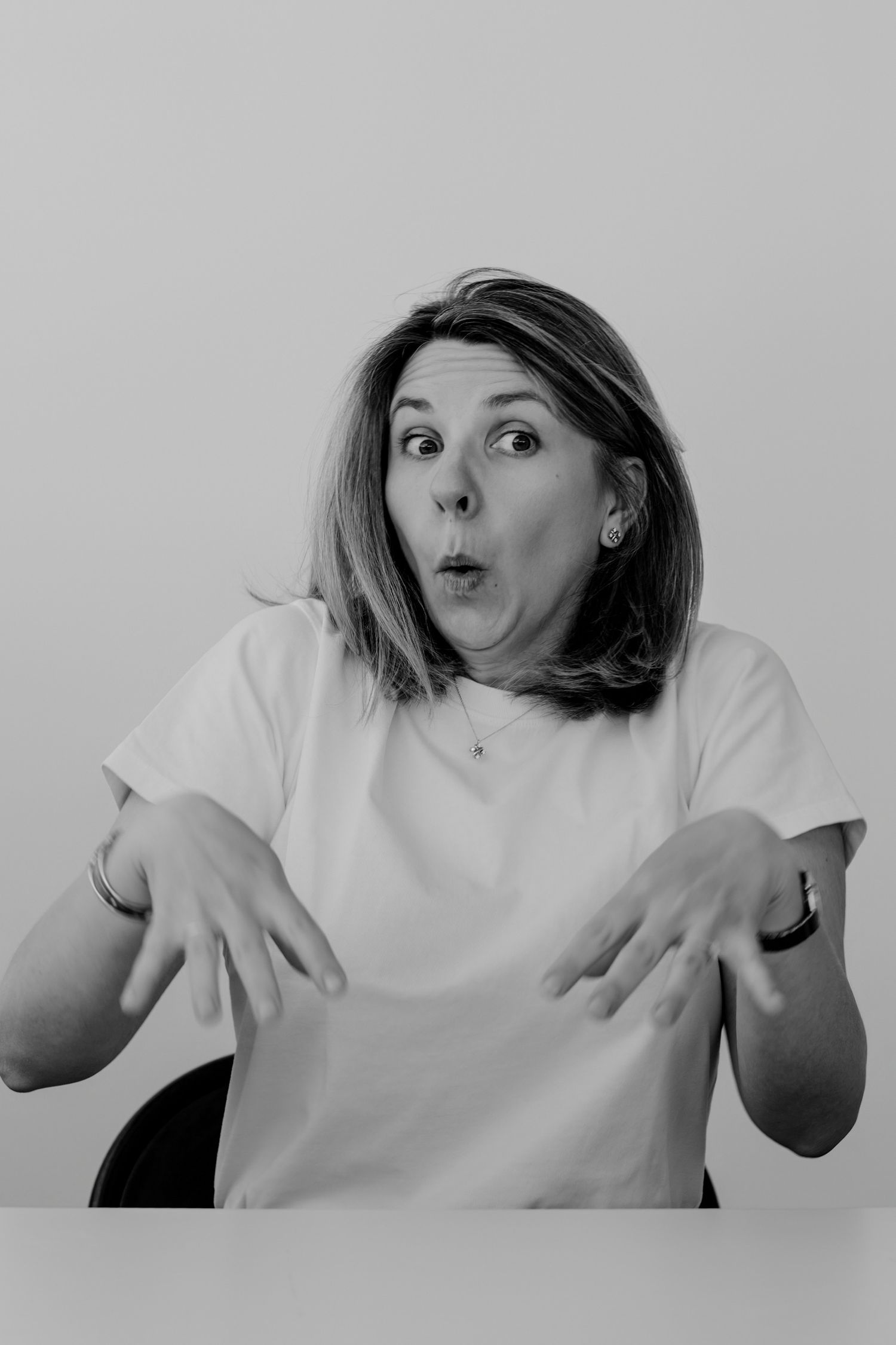 Black and white portrait series showing playful silly expressions and gestures in a white t-shirt.