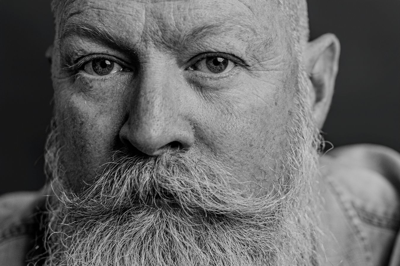 Detailed black and white headshot focusing on expressive eyes and flowing beard.