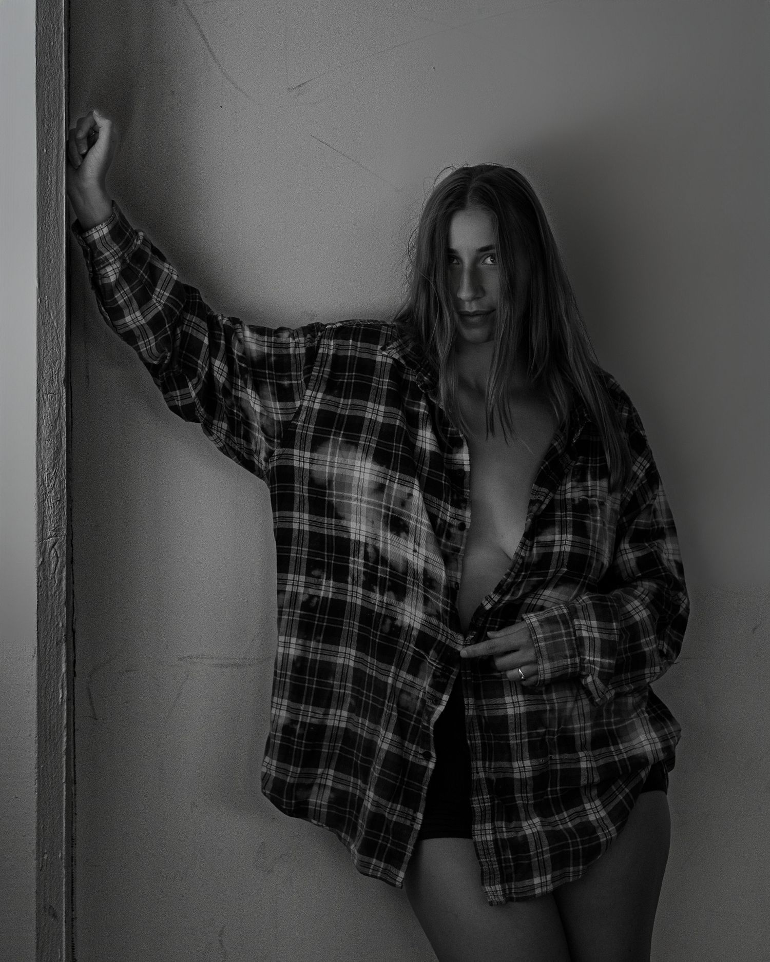 Moody grayscale portraits featuring a plaid shirt against plain wall.