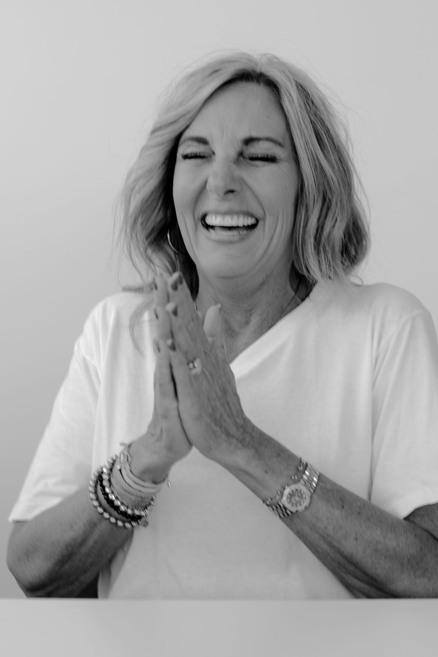 Black and white portrait series showing laughter and joy in different poses against a light background.
