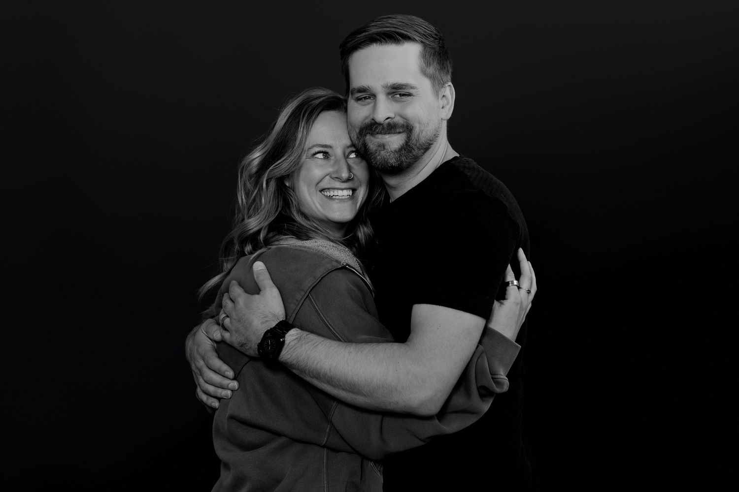 Candid black and white photo capturing couple laughing while embracing.