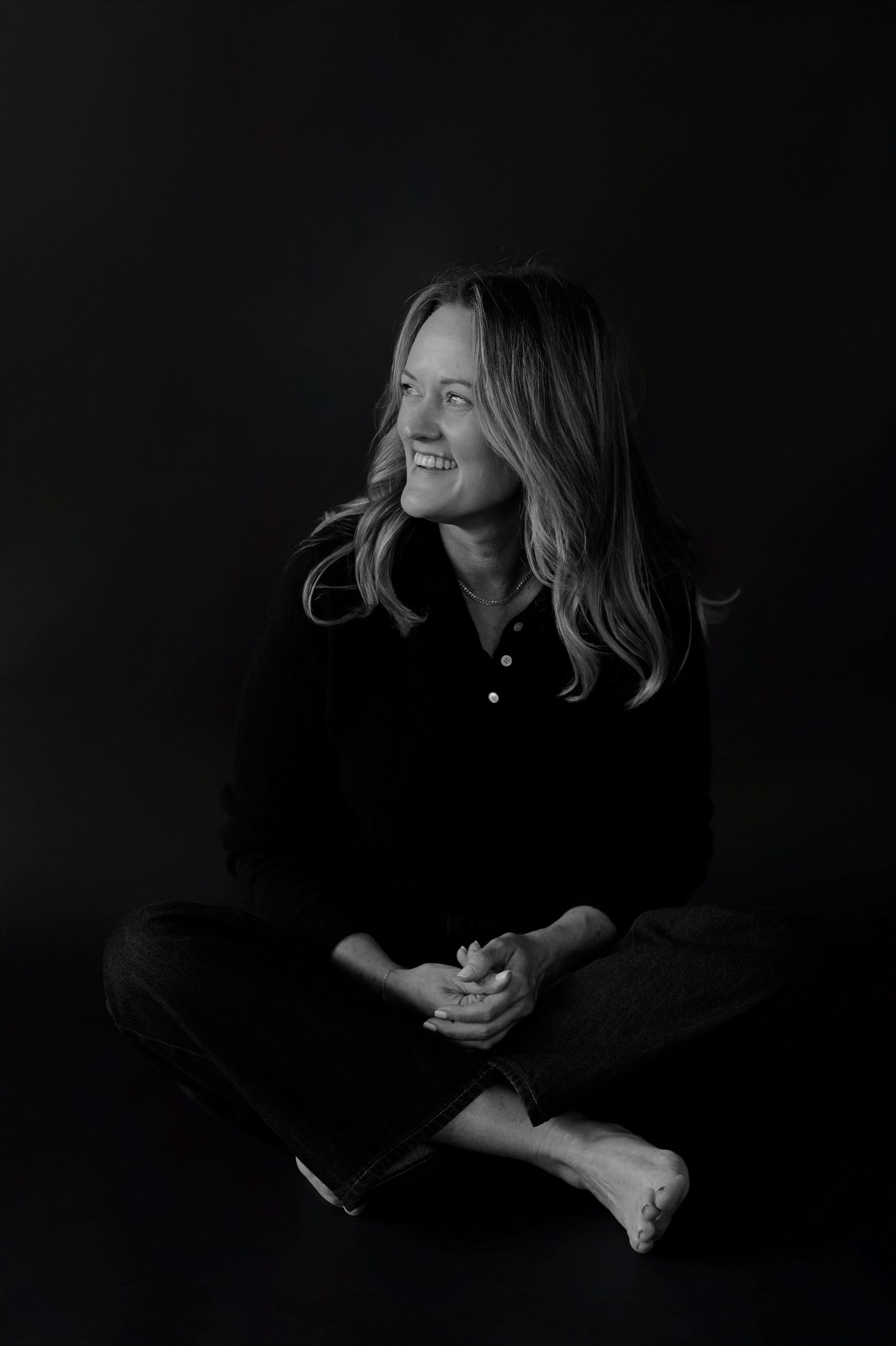 Low-key artistic portrait series showing figure in dark clothing against black background.