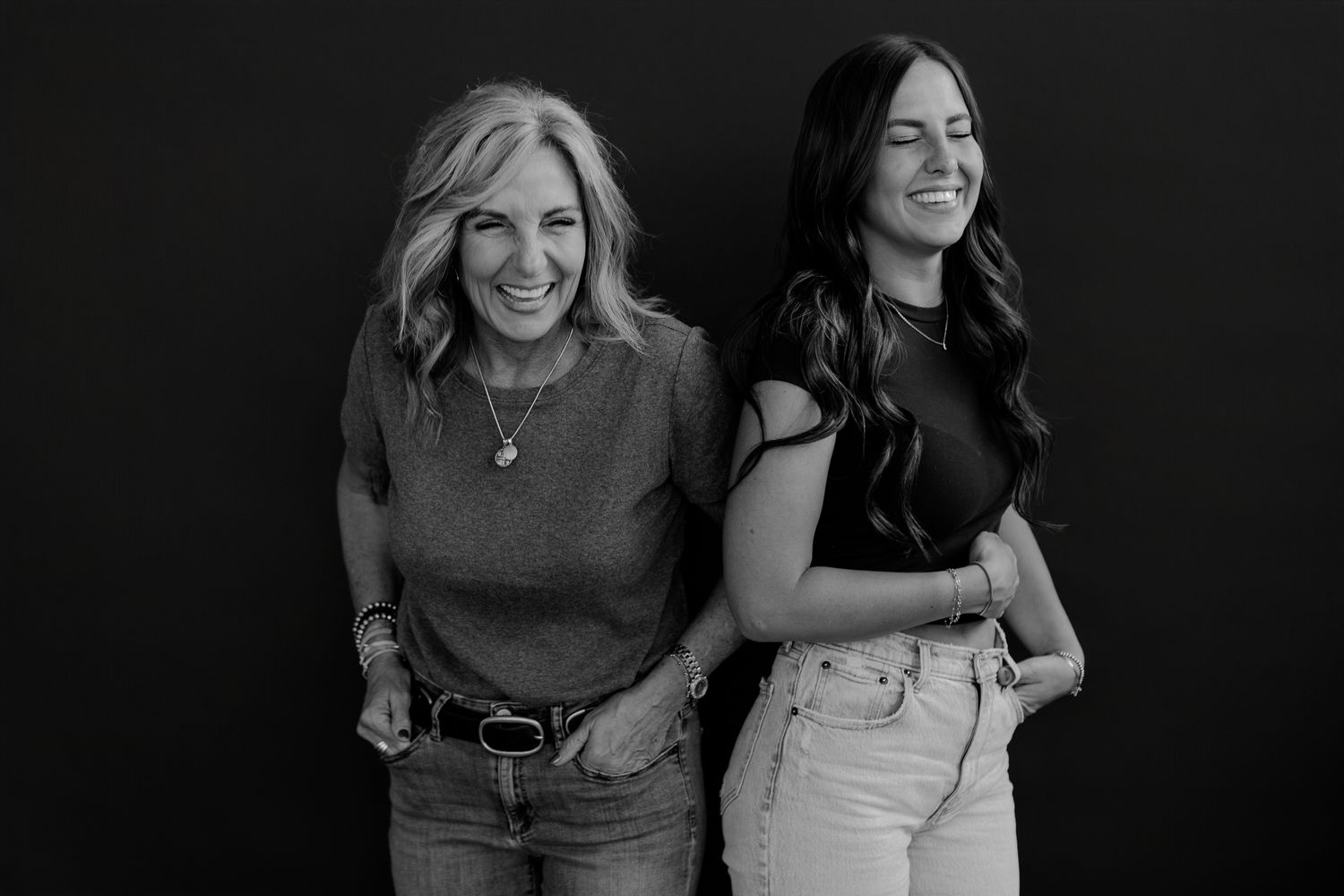 Studio portrait captures natural interaction between two women in monochromatic setting.
