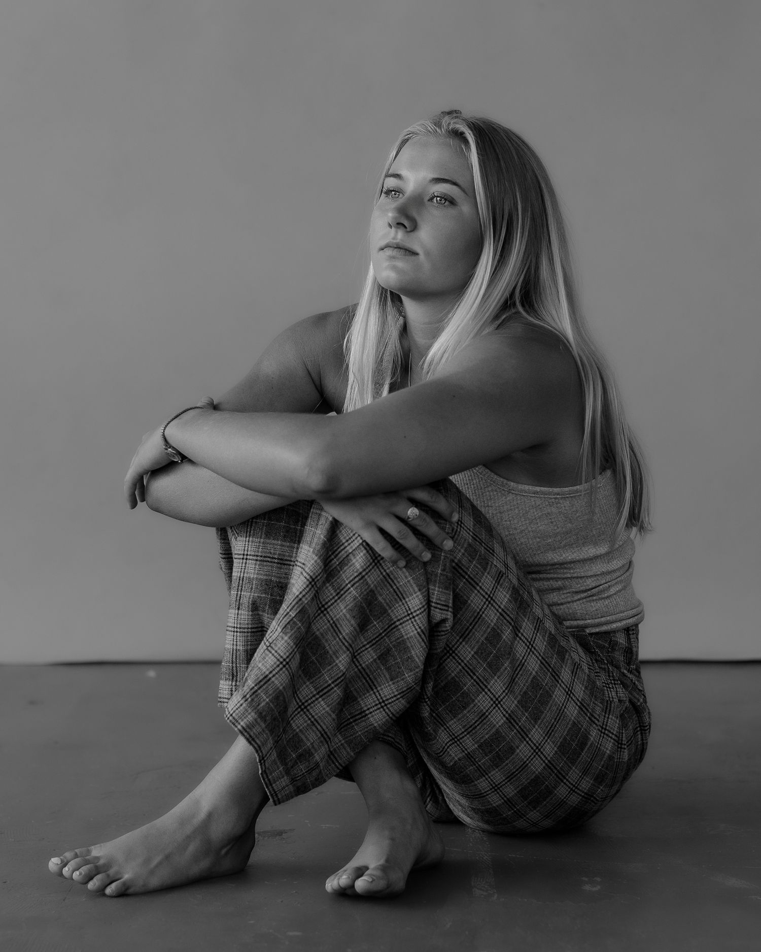 Artistic portrait series showing person in gray tank top and plaid pants in various seated poses.