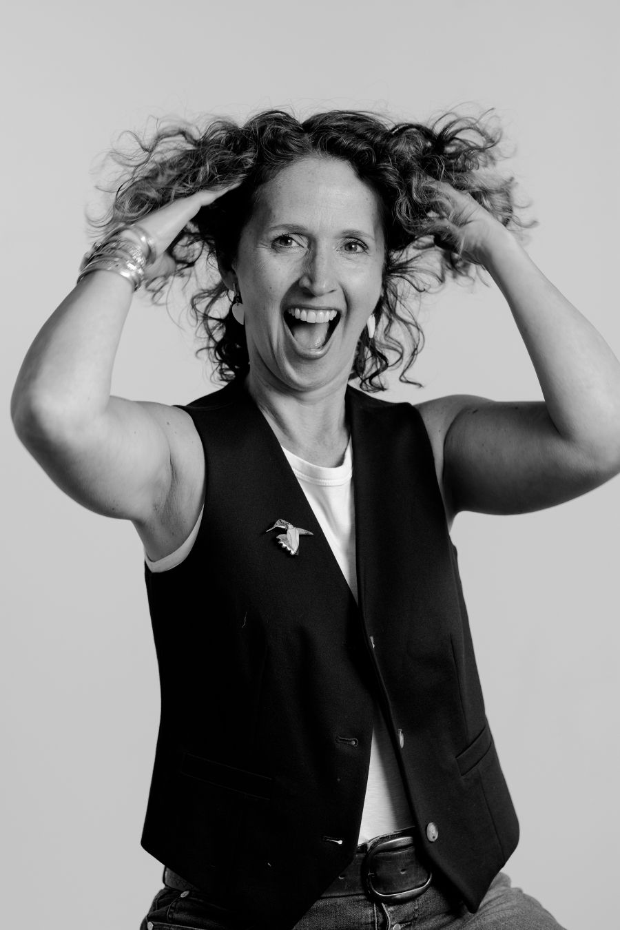 Energetic portrait series showing person with curly hair playfully posing in black vest.